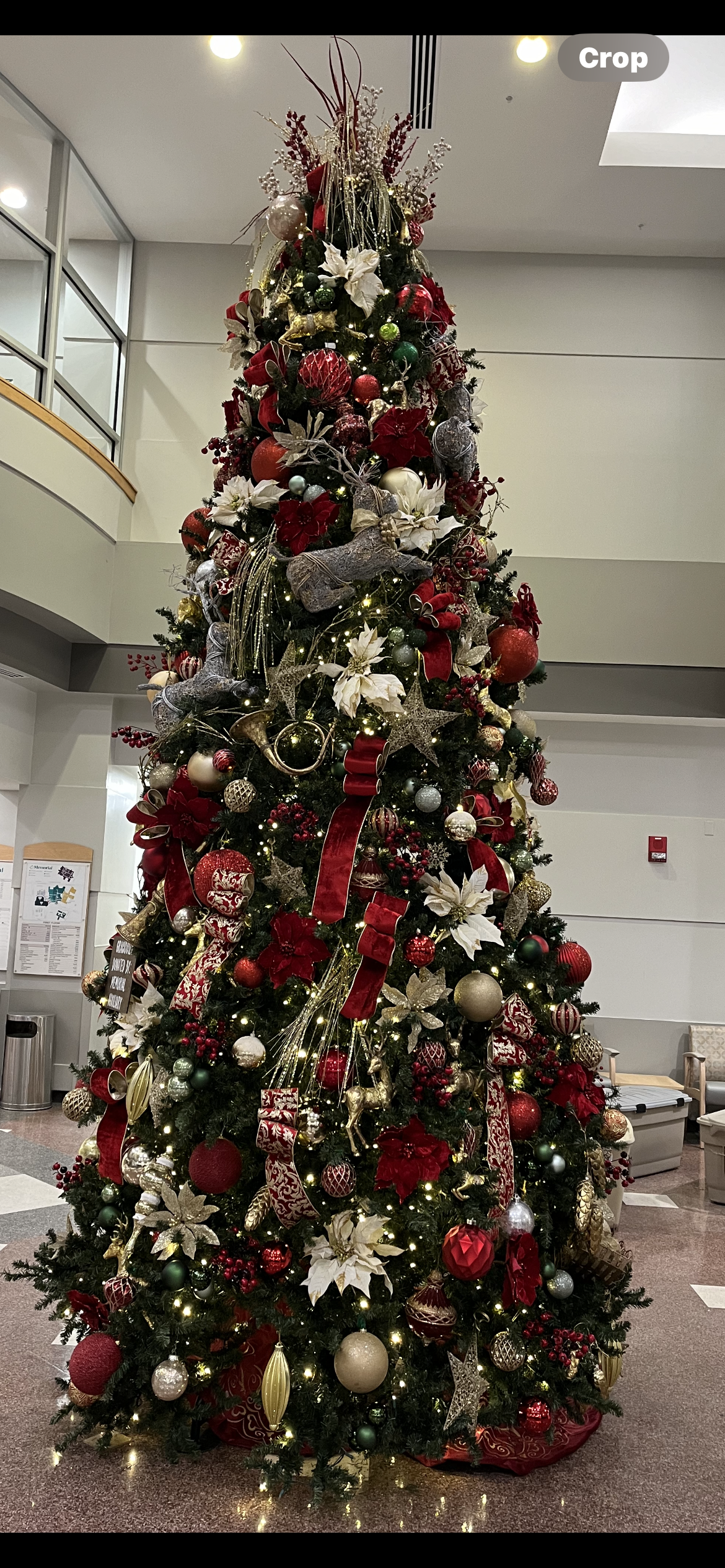 A large christmas tree decorated in red and white is sitting in a lobby.
