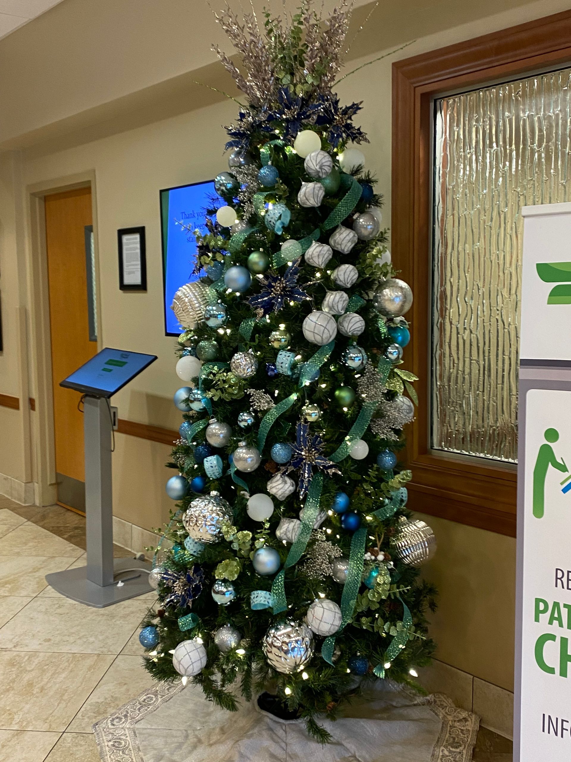 A christmas tree is sitting in a hallway next to a refrigerator.