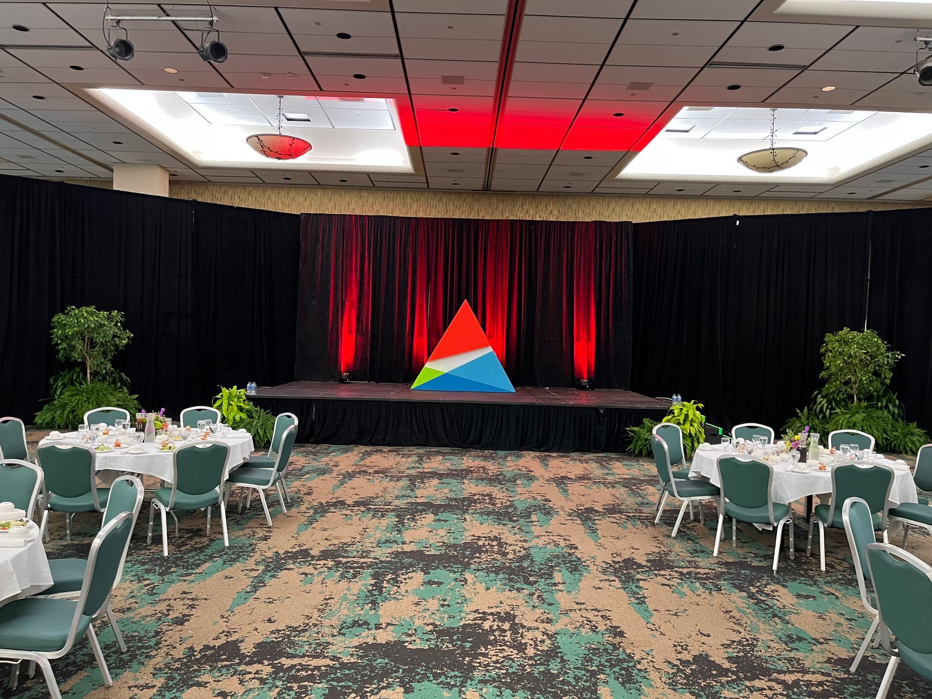 A large room with tables and chairs and a stage.