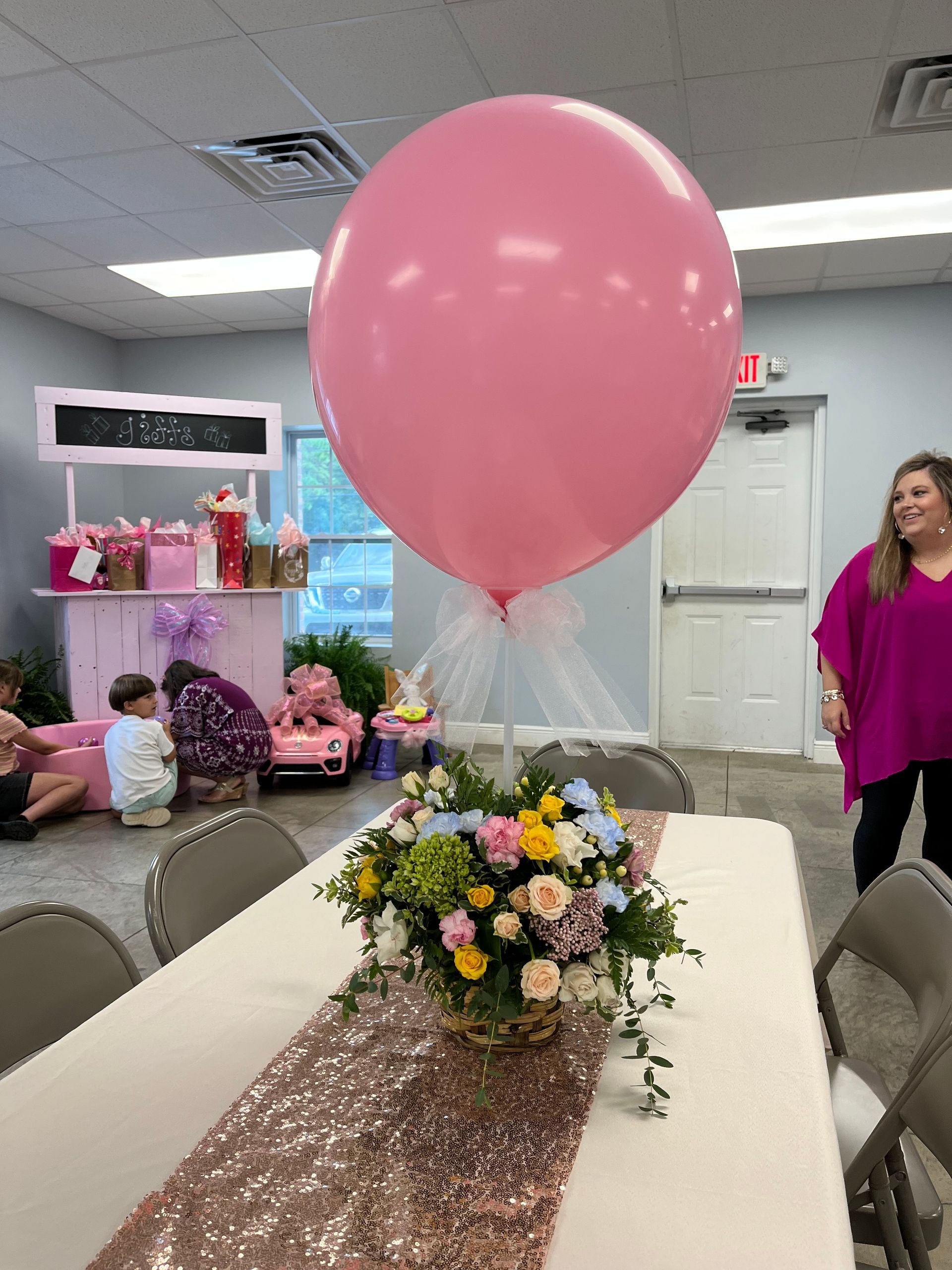 A large pink balloon is sitting on top of a table with flowers.