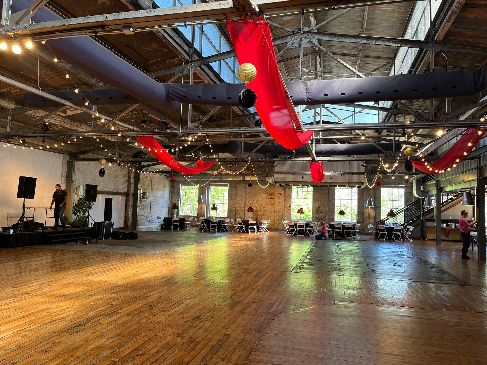 A large empty room with a dance floor and tables.