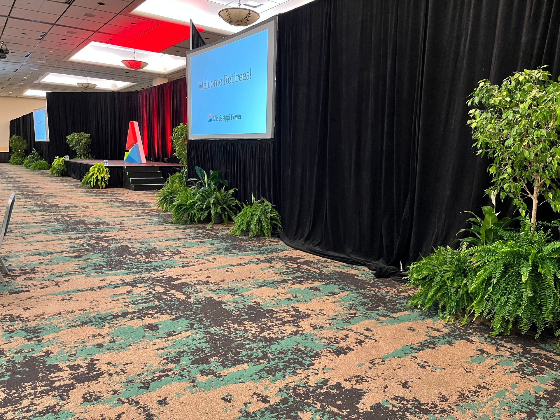 A large room with a stage and a projector screen.