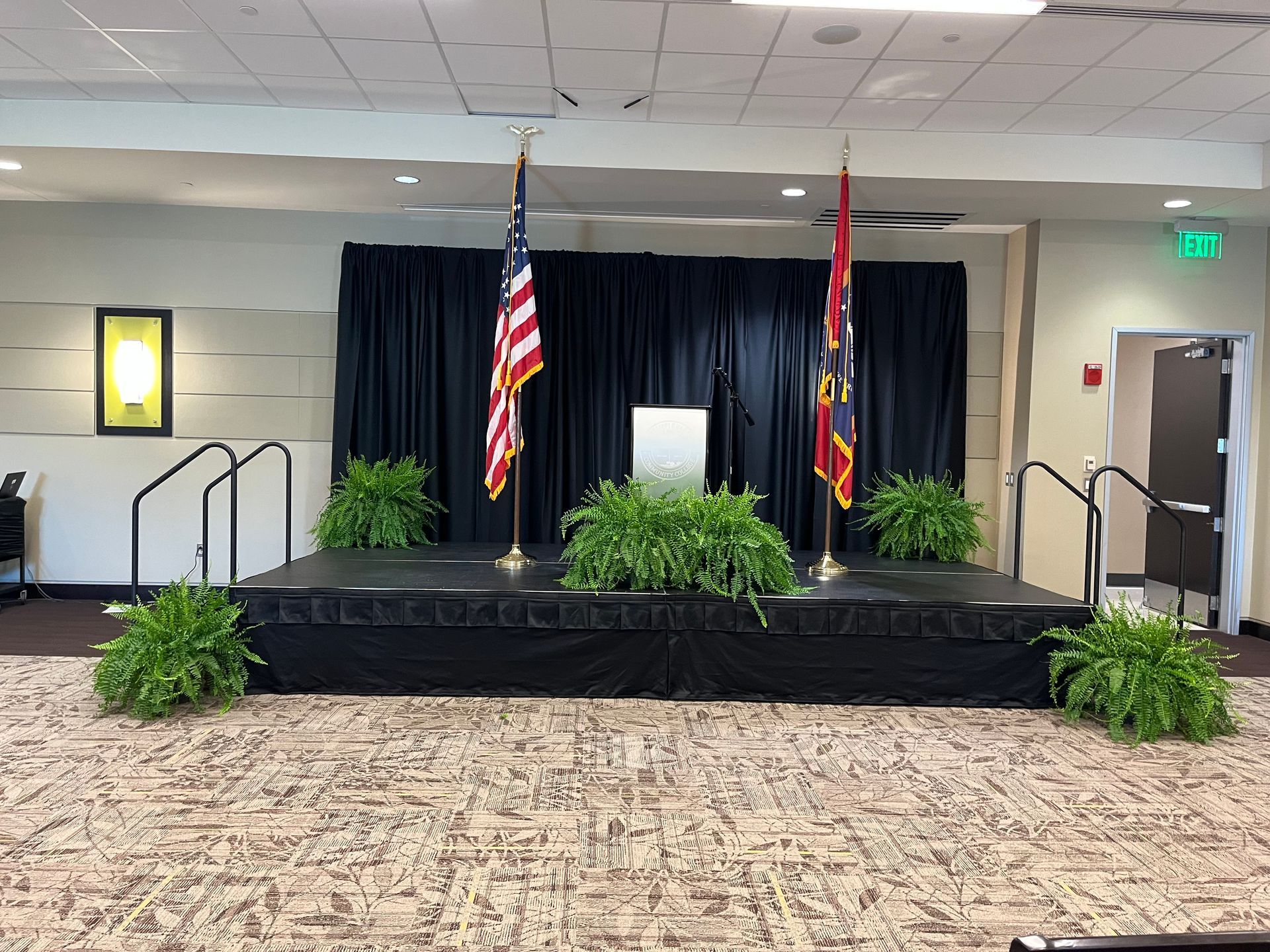 A stage in a room with flags and plants on it