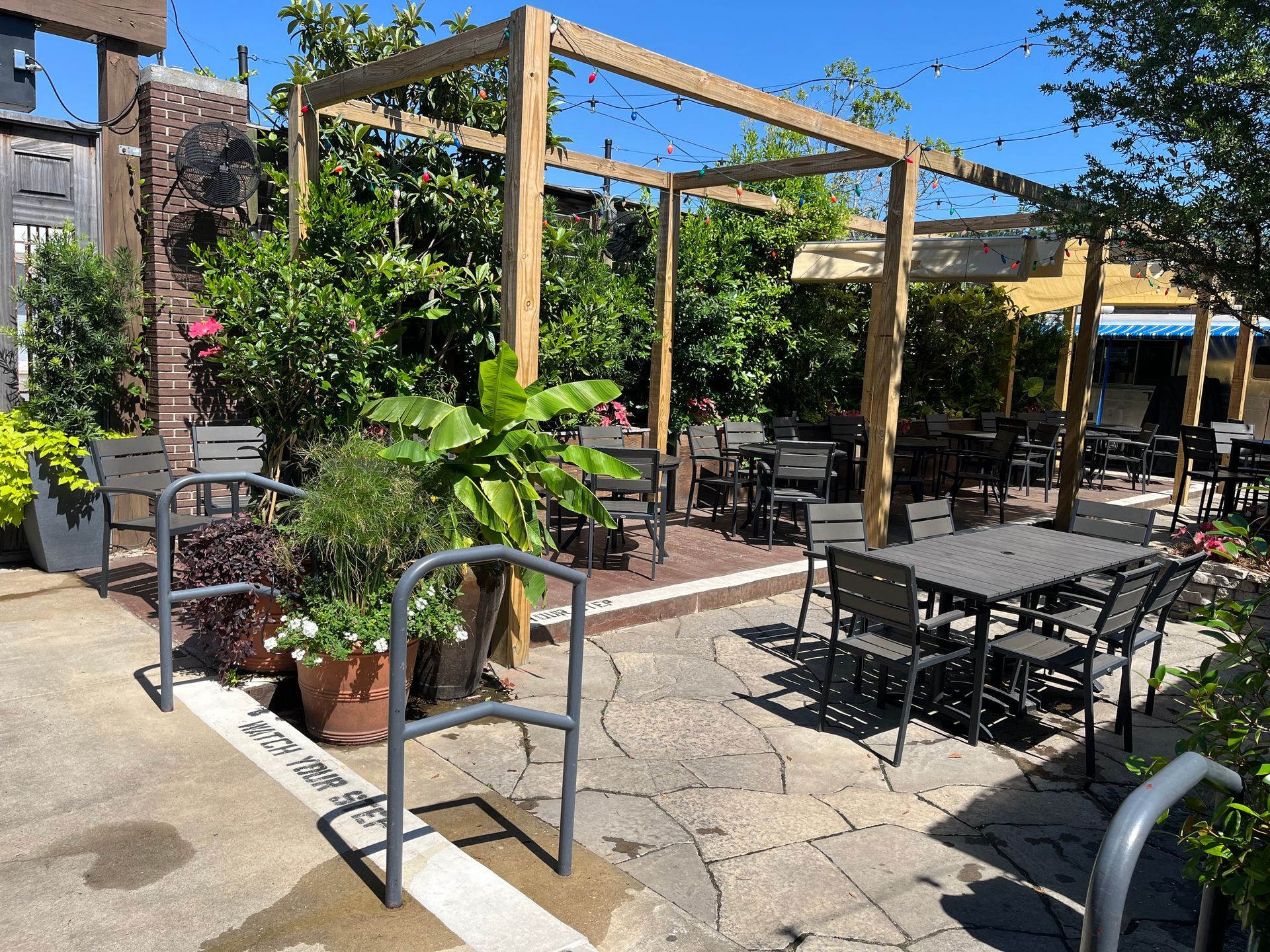 A patio with tables and chairs under a pergola