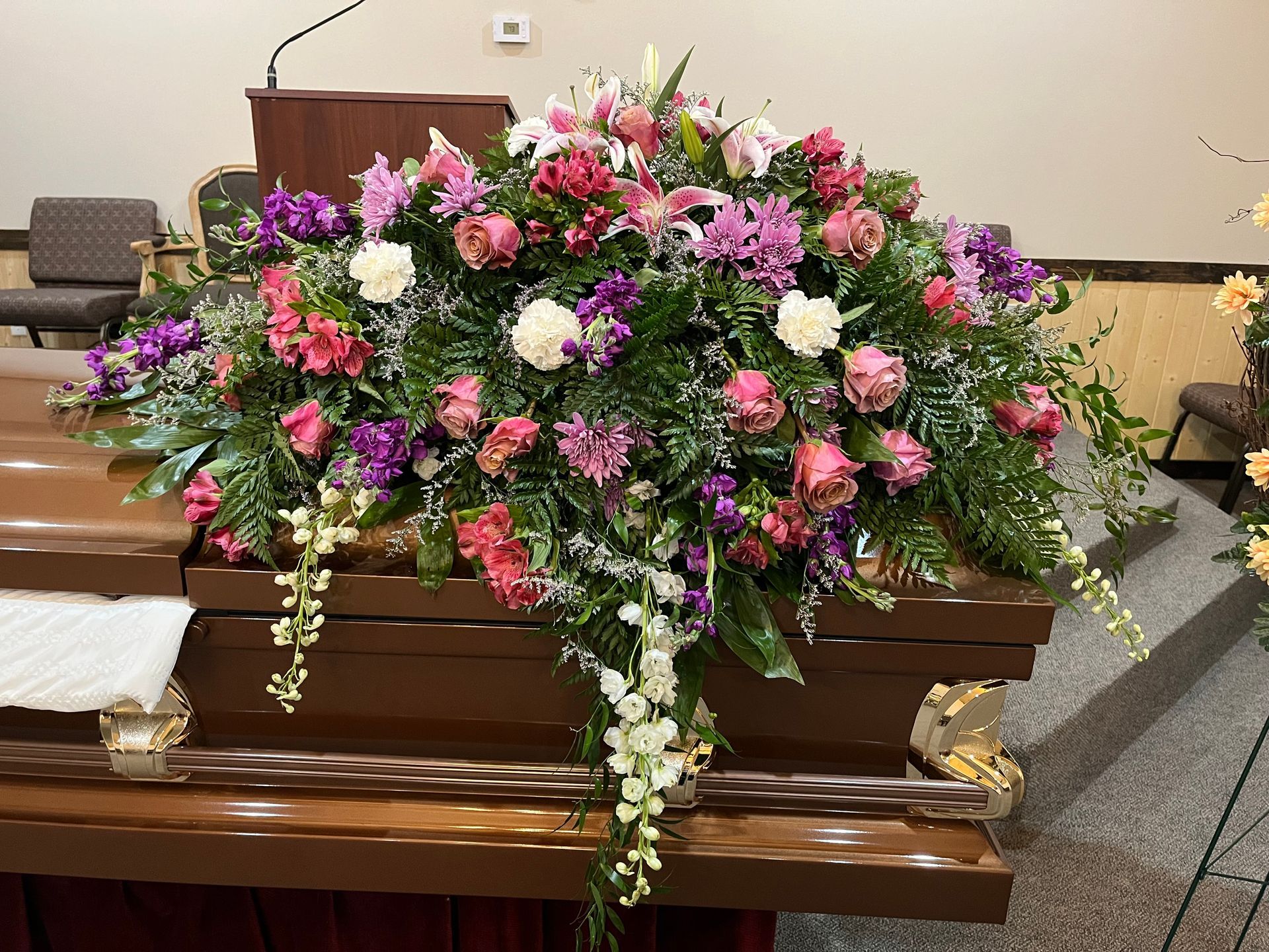 A coffin is decorated with purple and pink flowers in a church.
