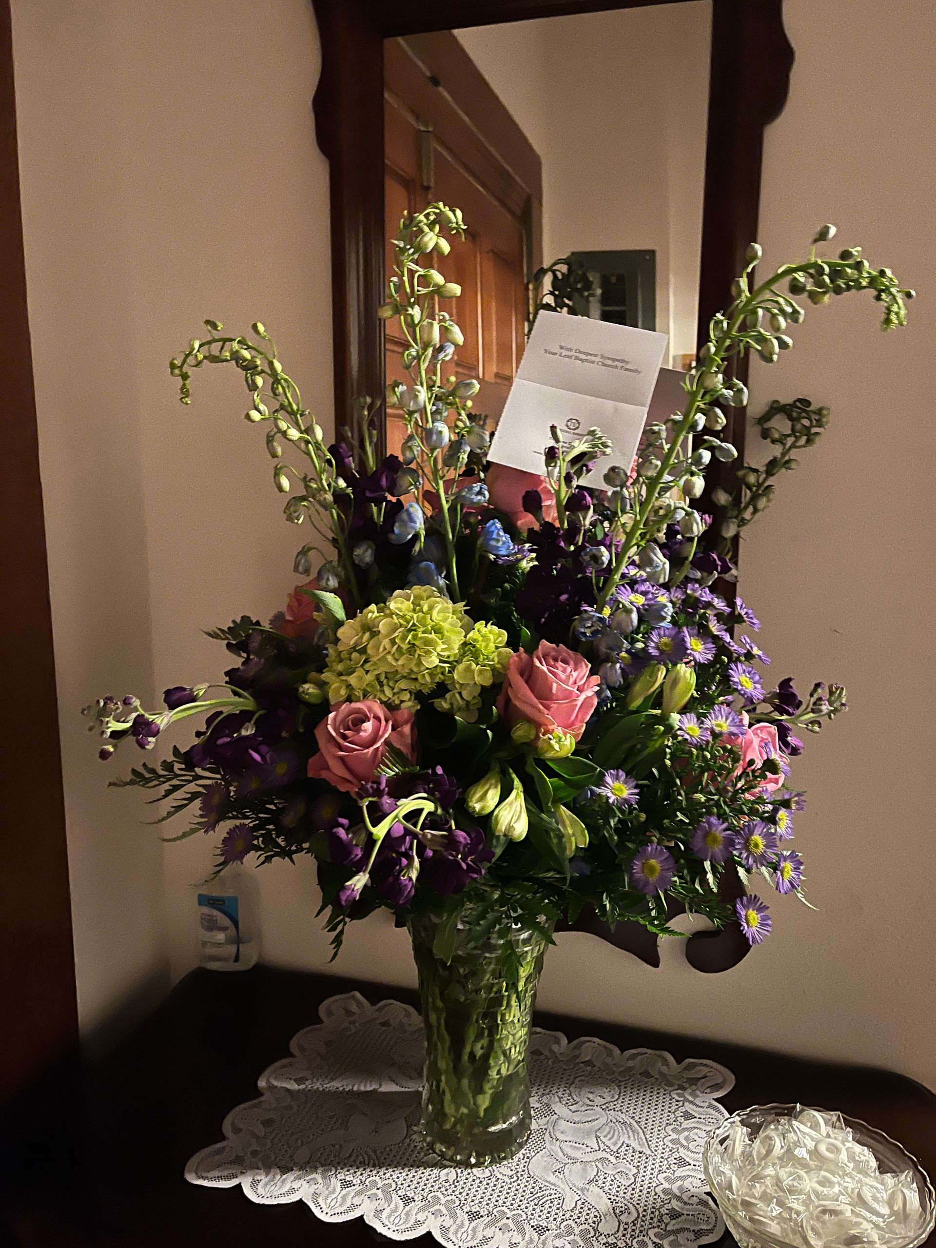 A vase of flowers sits on a table in front of a mirror