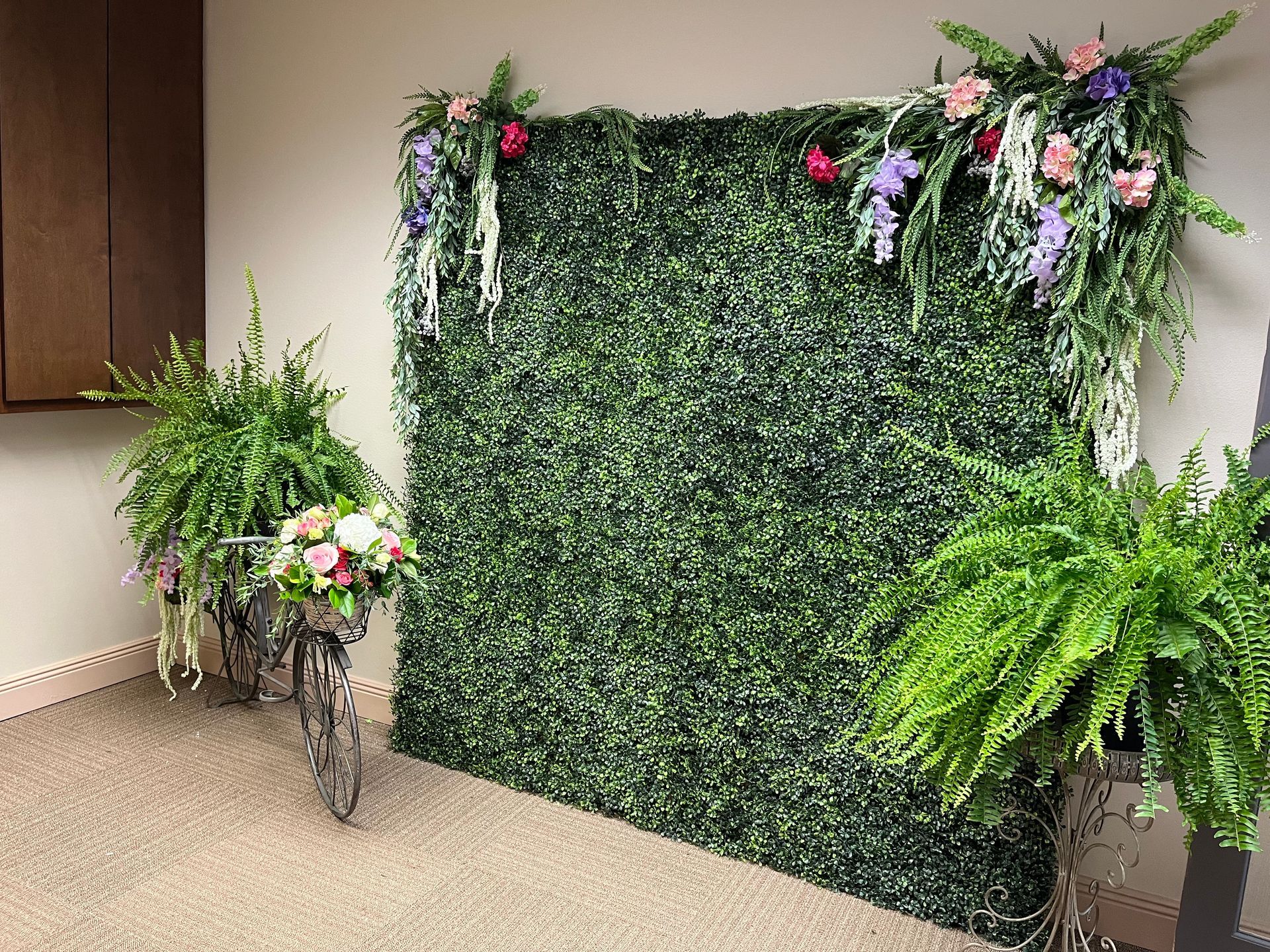 A green wall with flowers and ferns on it in a room.