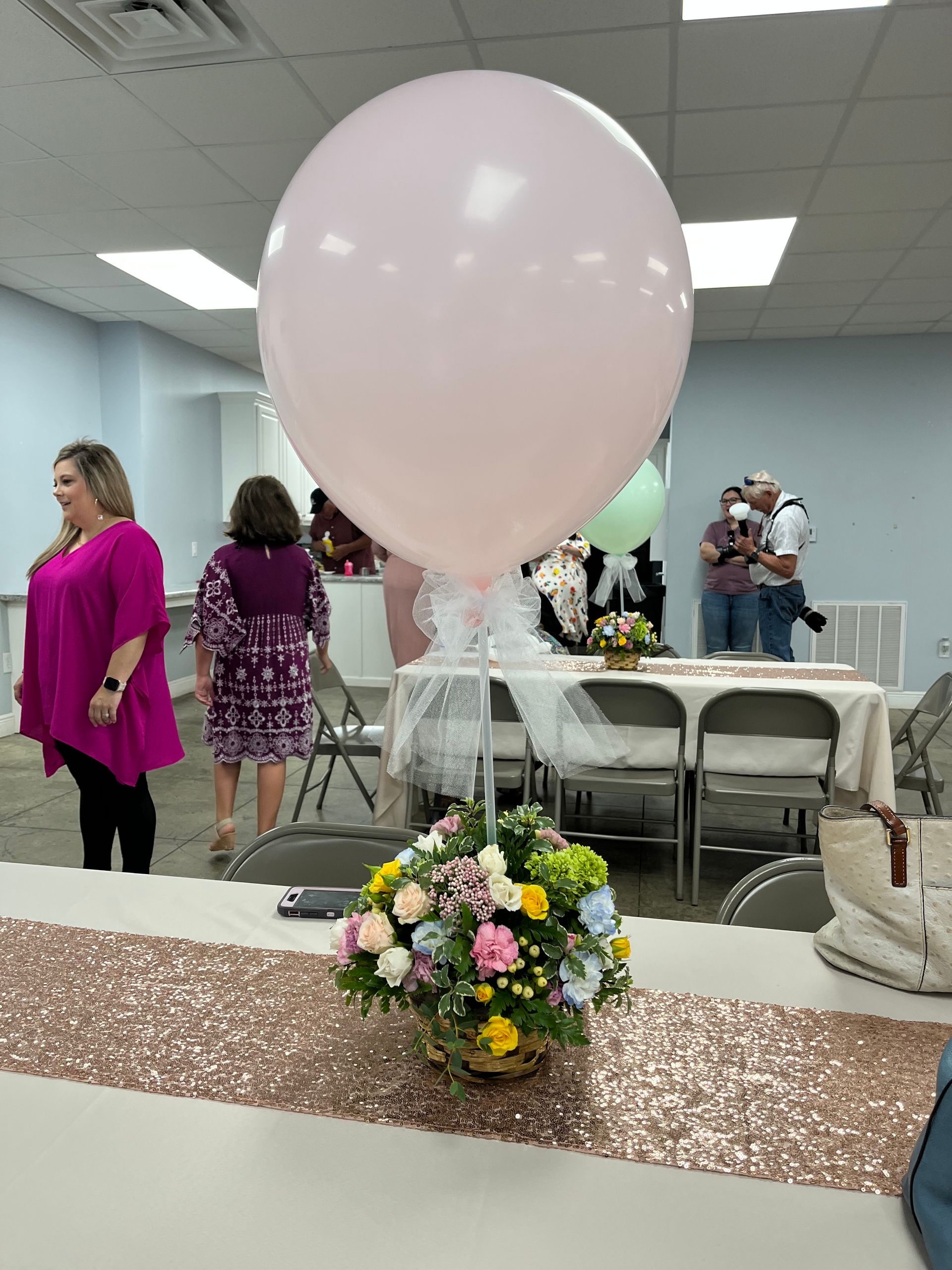 A pink balloon is sitting on top of a table with flowers.
