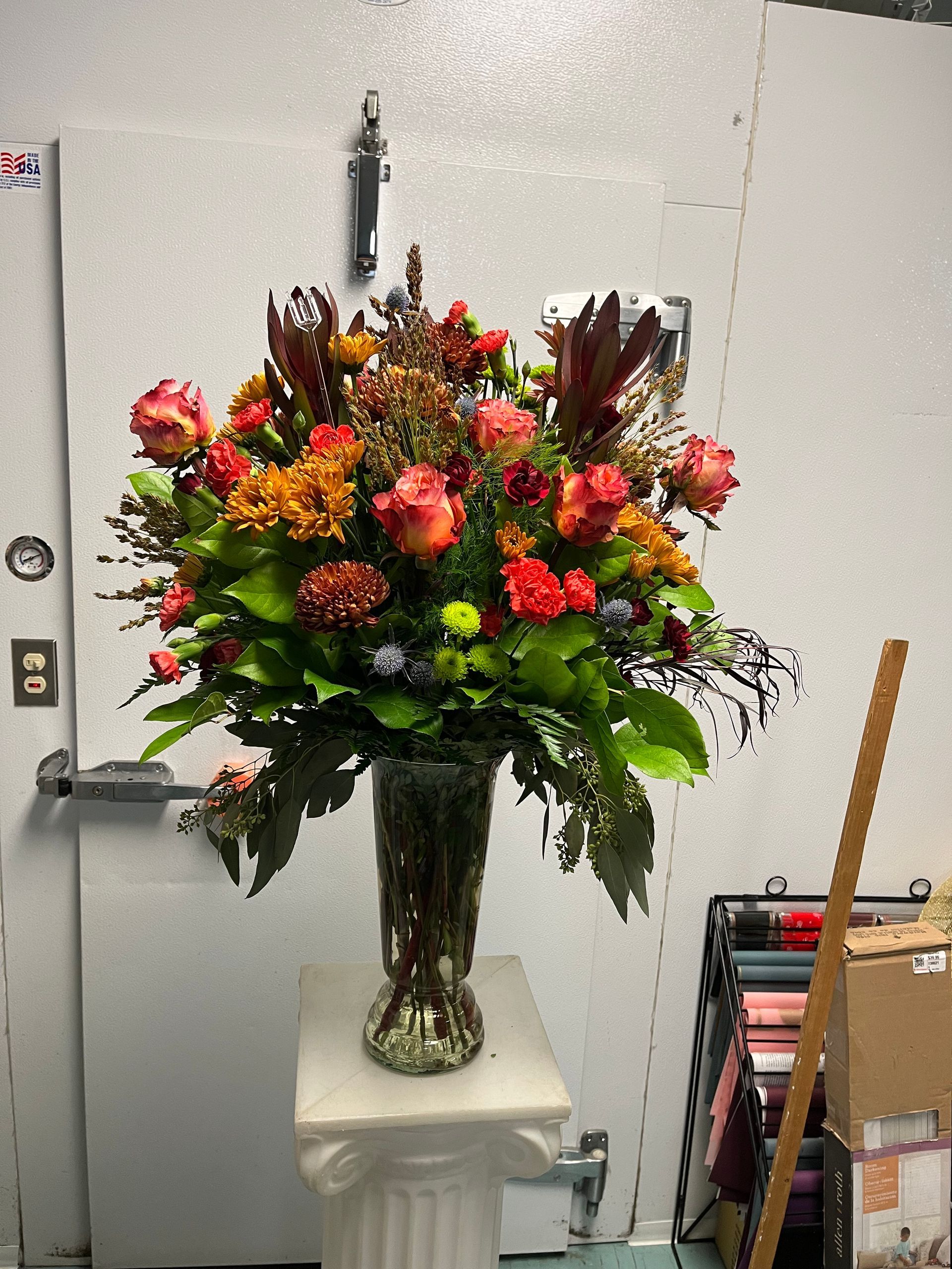 A vase filled with flowers is sitting on a pedestal.