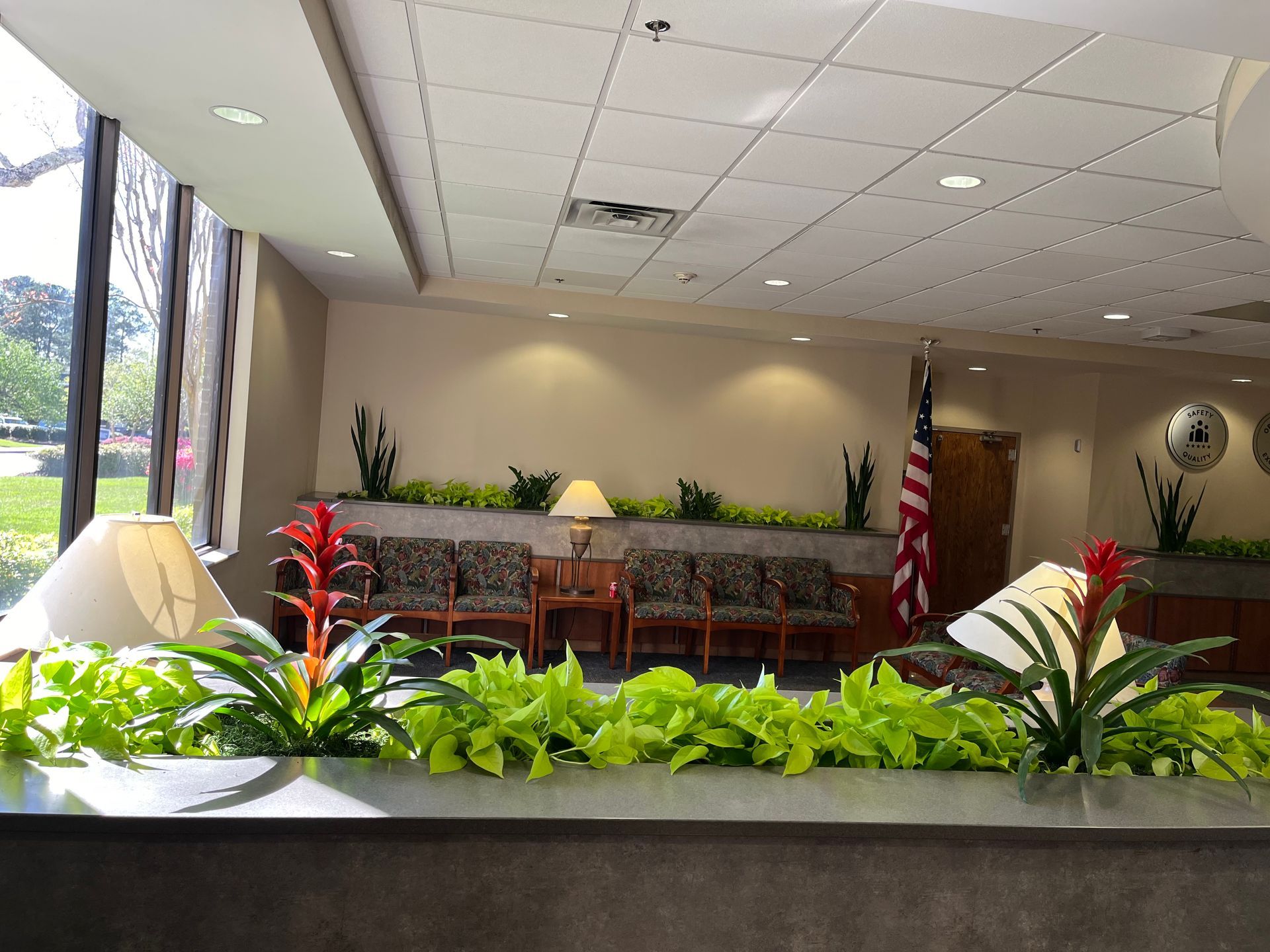 A waiting room with chairs , lamps , plants and an american flag