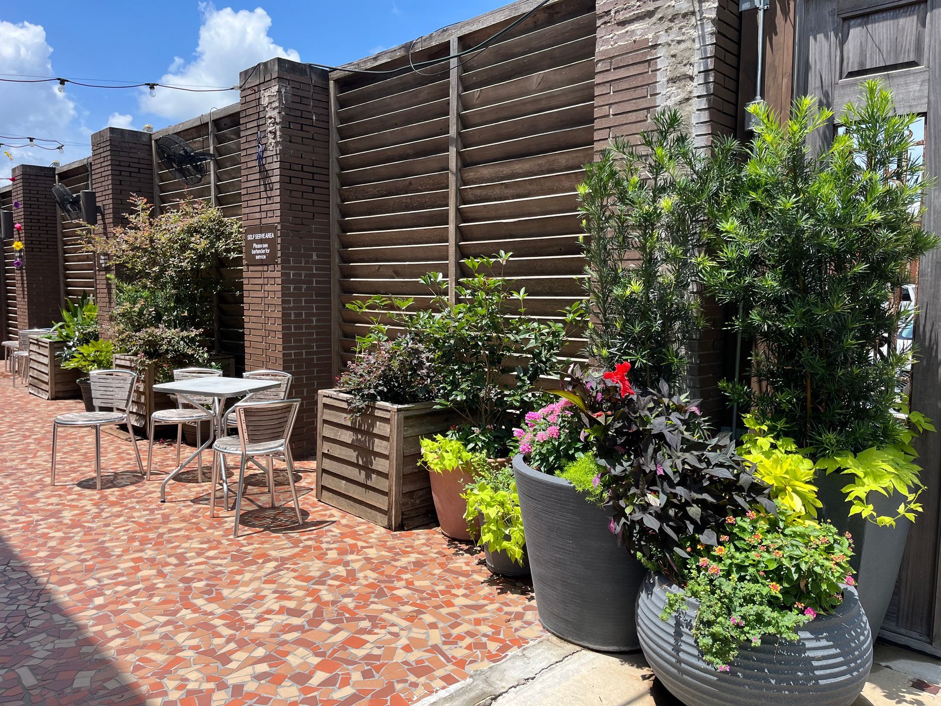 A patio with tables and chairs and potted plants.