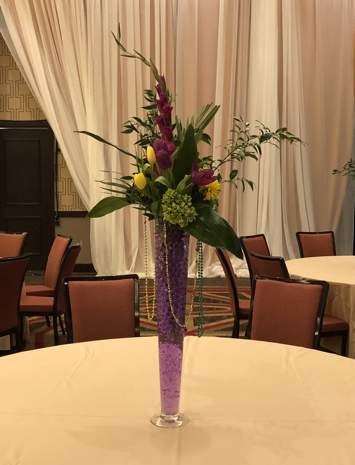 A tall vase filled with flowers is sitting on a table.
