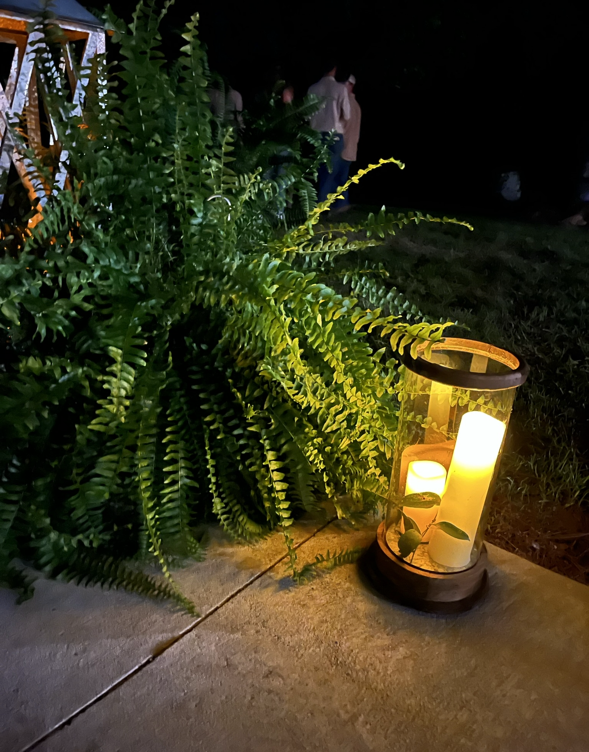 A lantern with a candle inside of it is lit up at night.