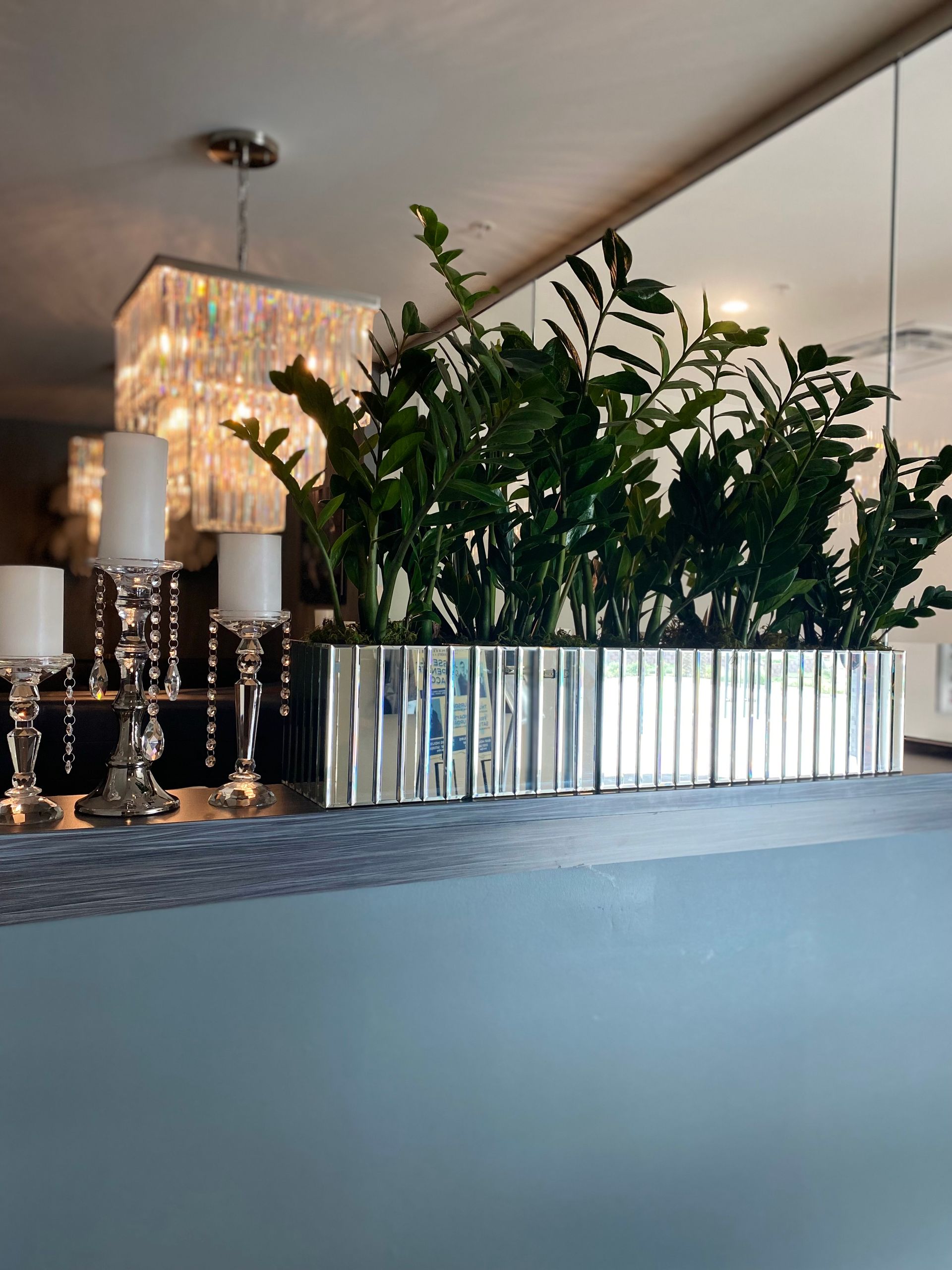 A large mirrored planter filled with plants and candles