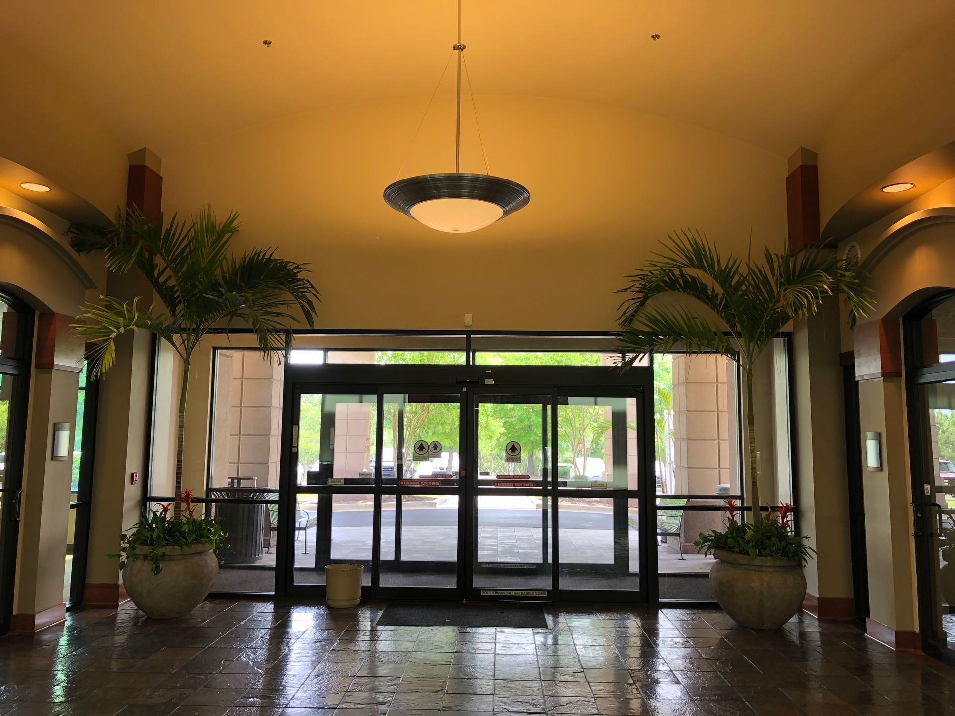 A lobby with a sliding glass door and potted plants