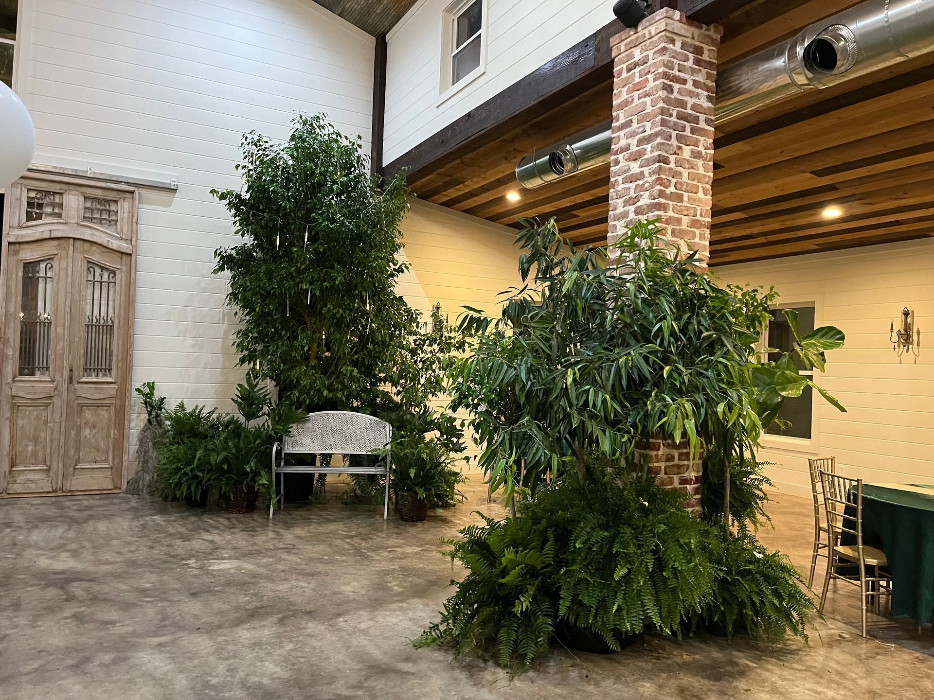 A large room with lots of plants and a brick chimney.