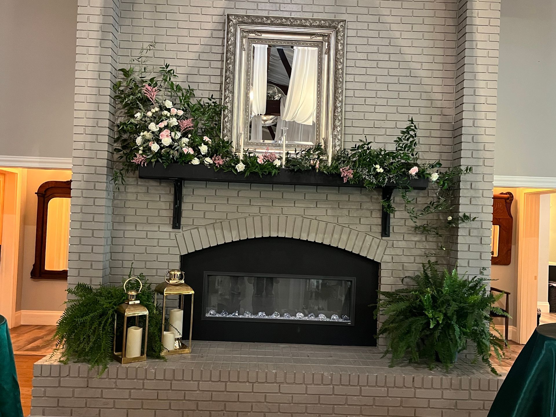 A fireplace decorated with flowers and candles in a living room.