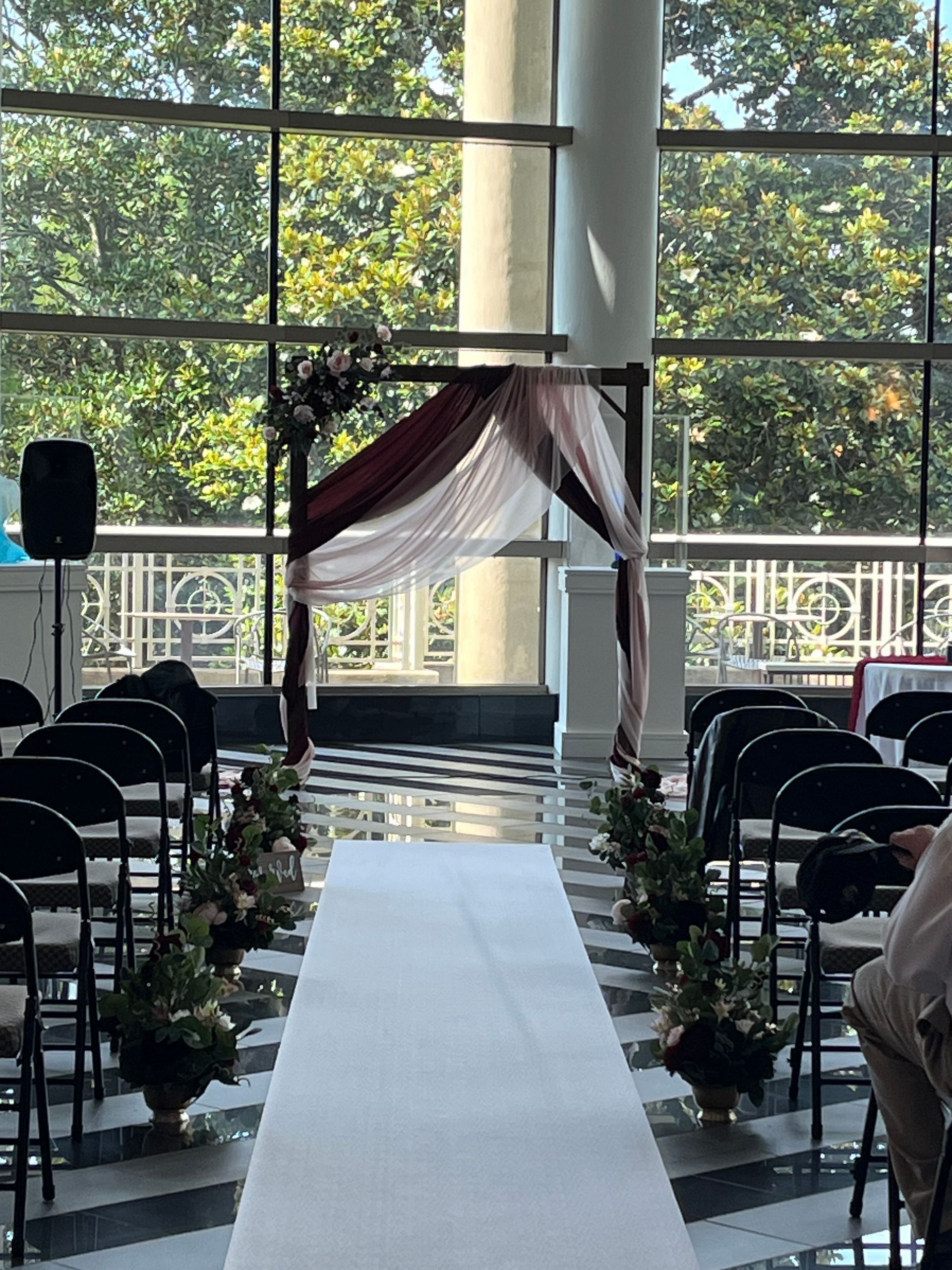 A wedding ceremony is taking place in a large room with lots of windows.