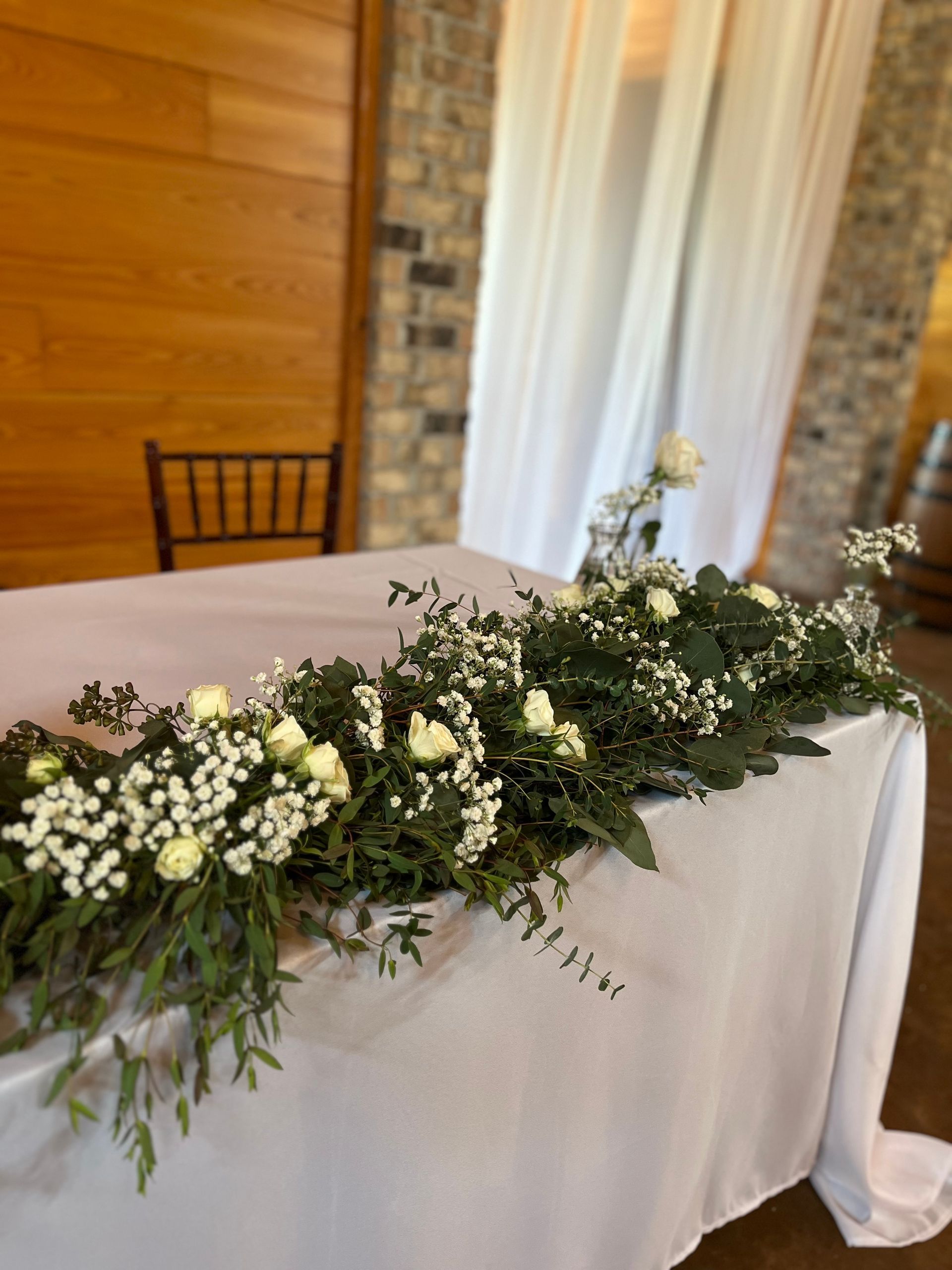 A long table with flowers and baby 's breath on it.