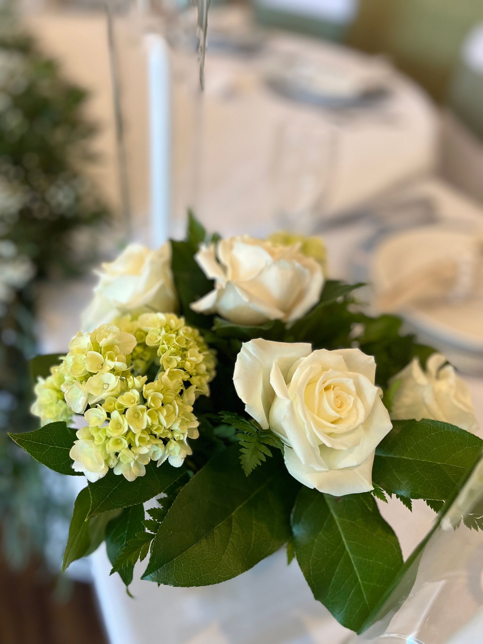 A bouquet of white roses and green hydrangea flowers on a table.