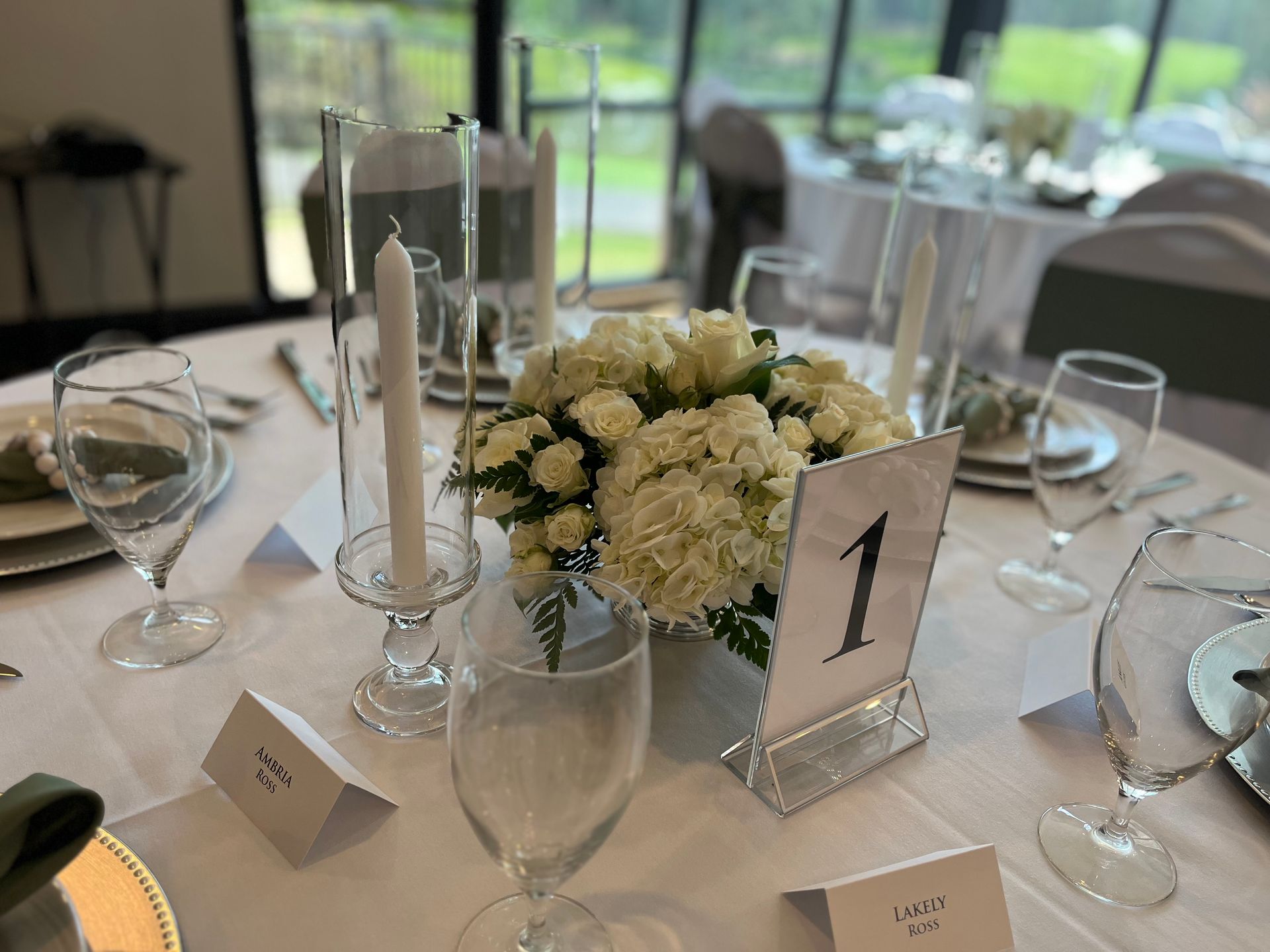 A table set for a wedding reception with flowers and candles on it.