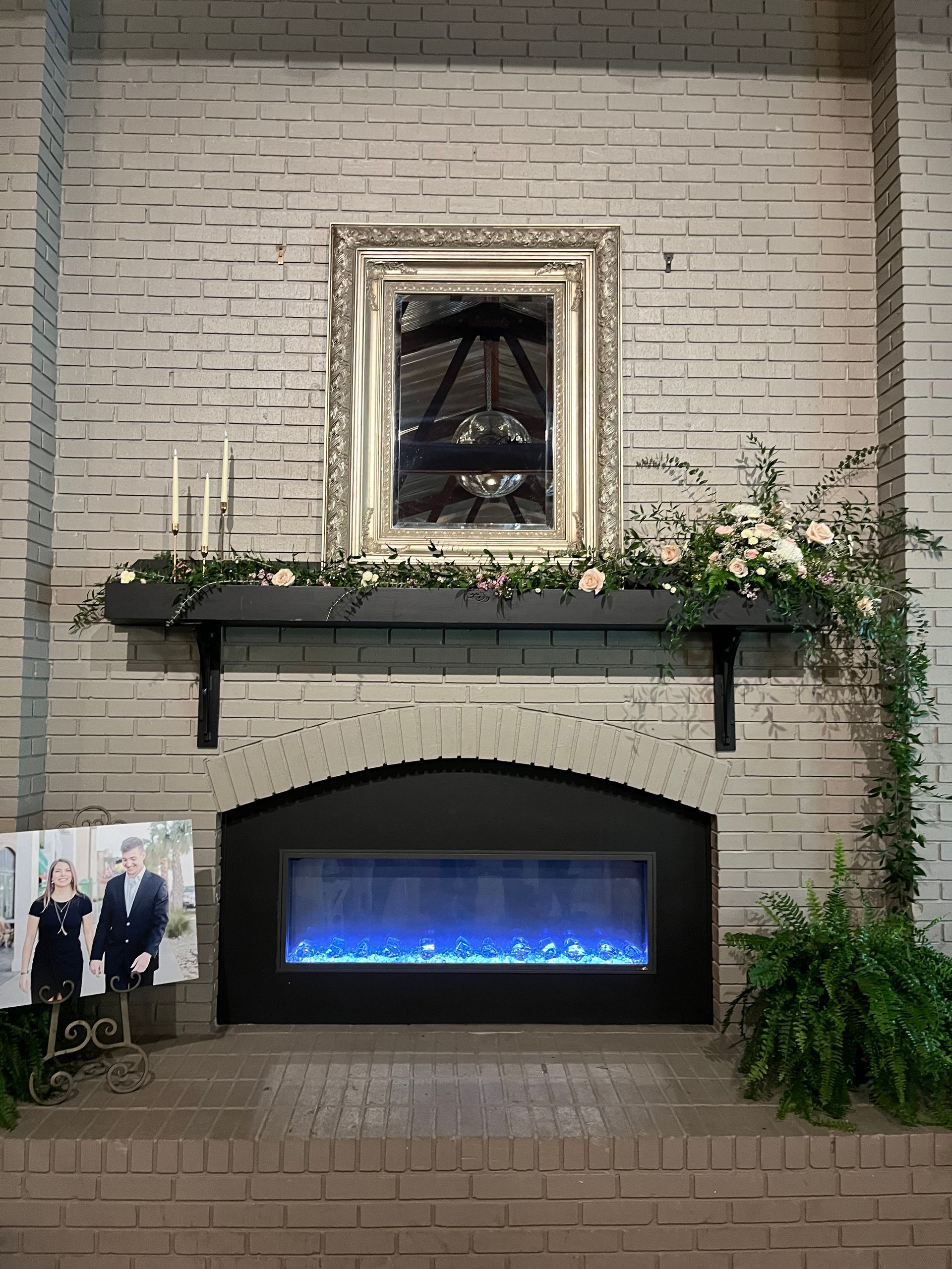 A fireplace with a picture of a man and woman on the mantle.