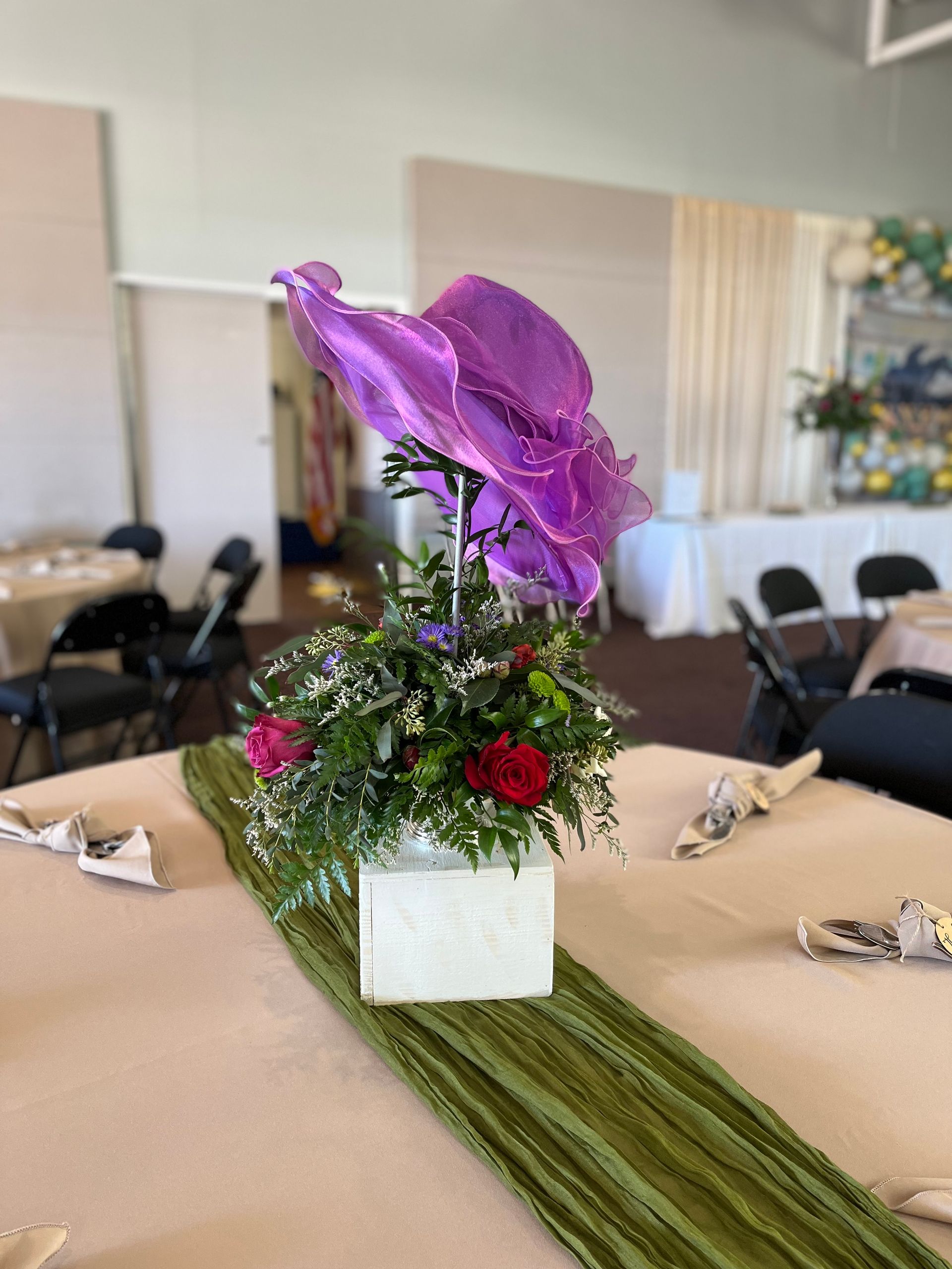A table with a vase of flowers and a purple flower on it.