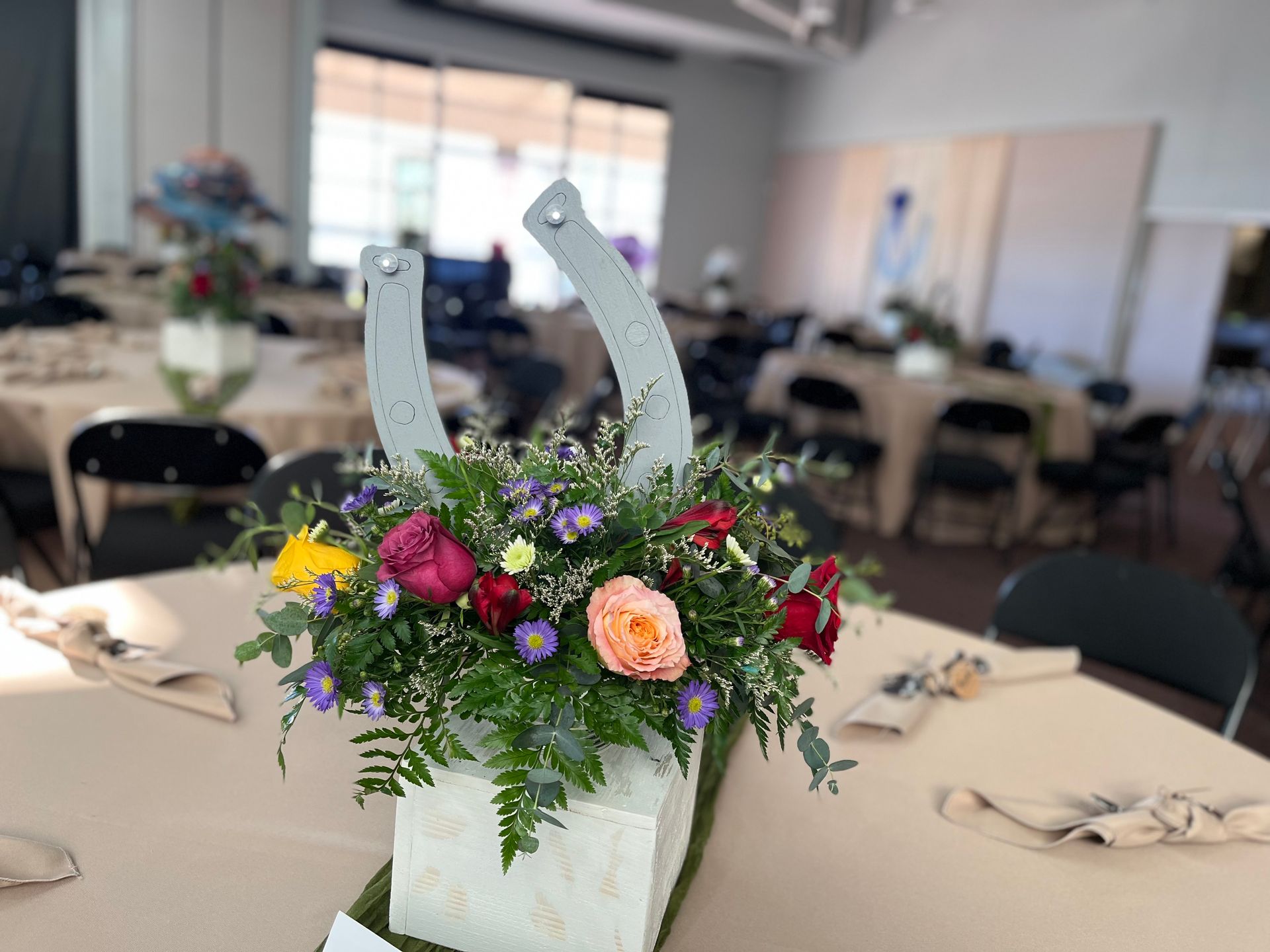 A horseshoe with flowers in it is sitting on a table.