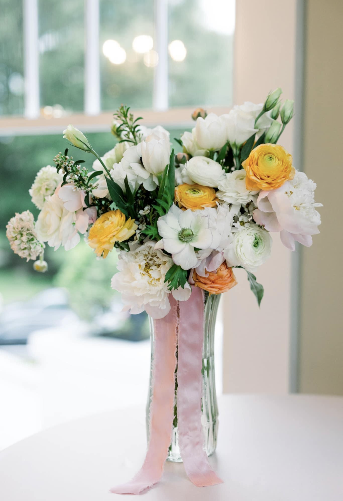 A vase filled with white and yellow flowers is sitting on a table.