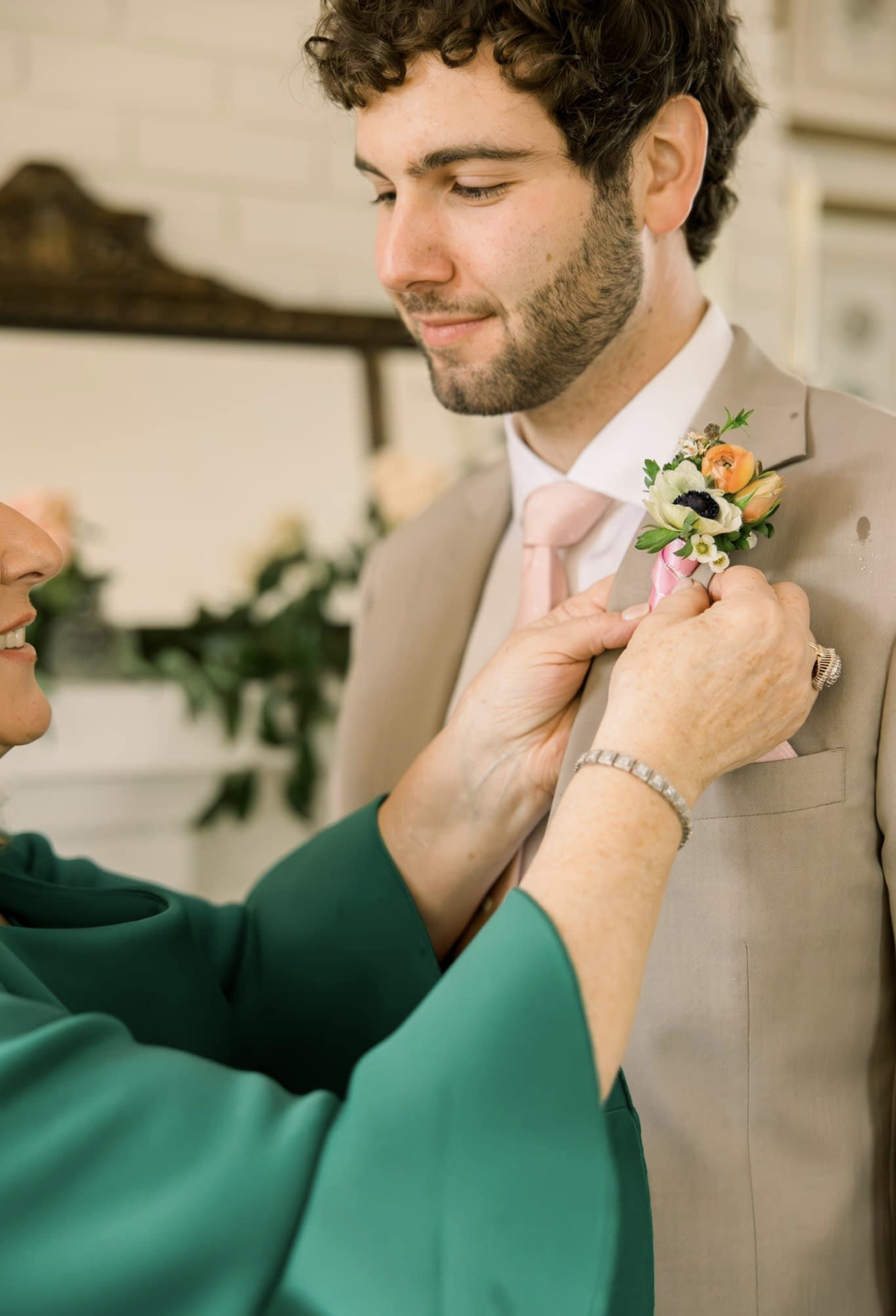 A woman is helping a groom with his boutonniere.