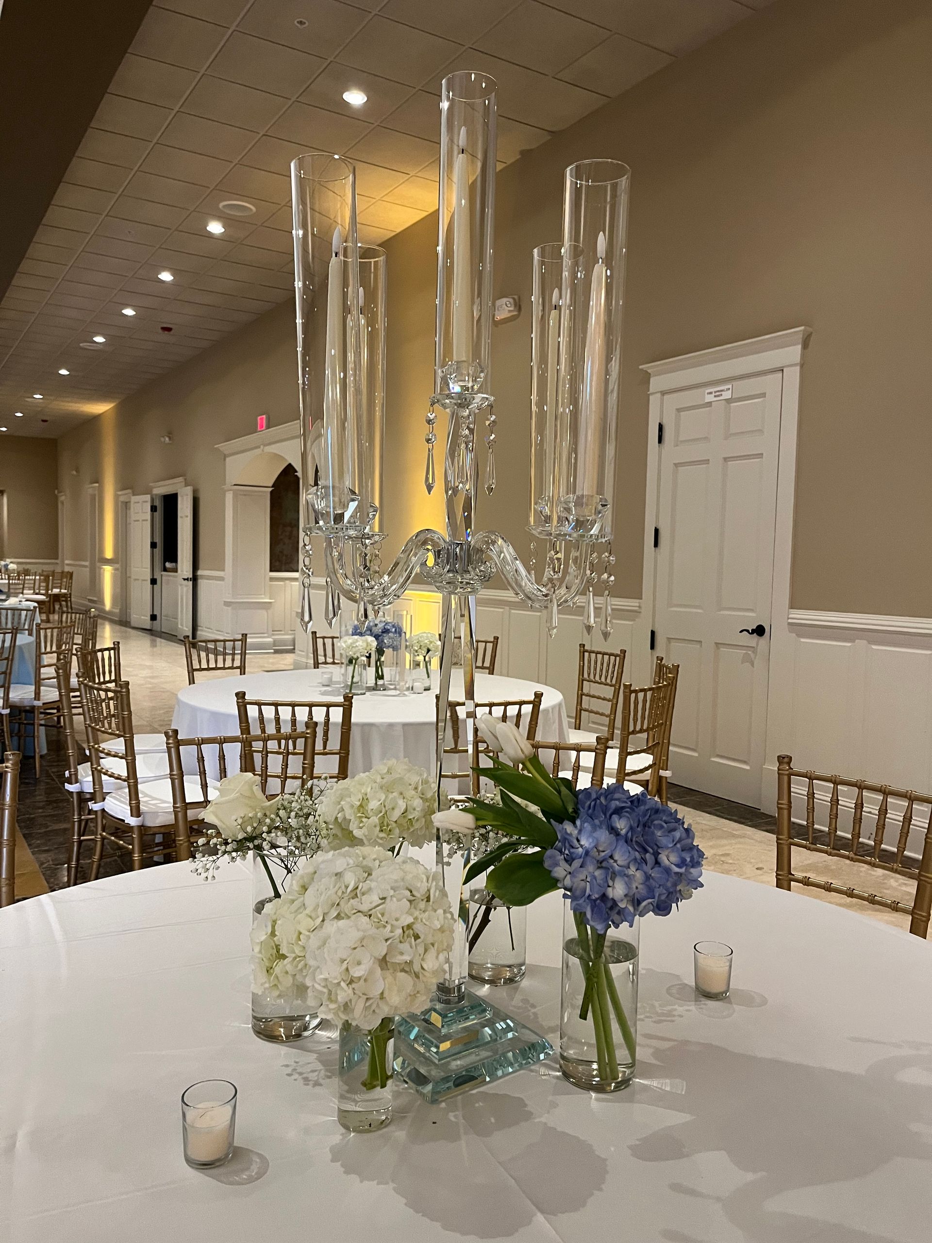 A table with a vase of flowers and candles on it.
