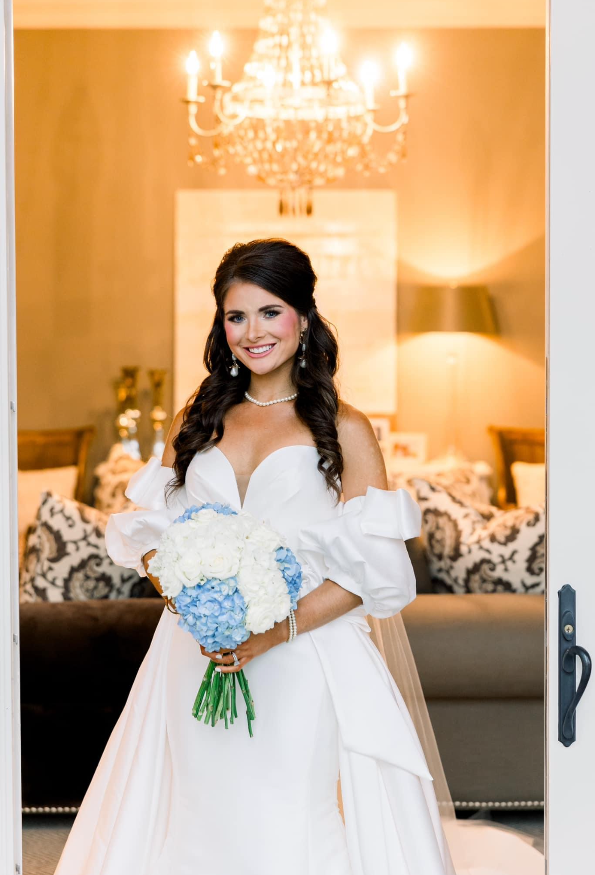 A bride in a white dress is holding a bouquet of blue and white flowers.