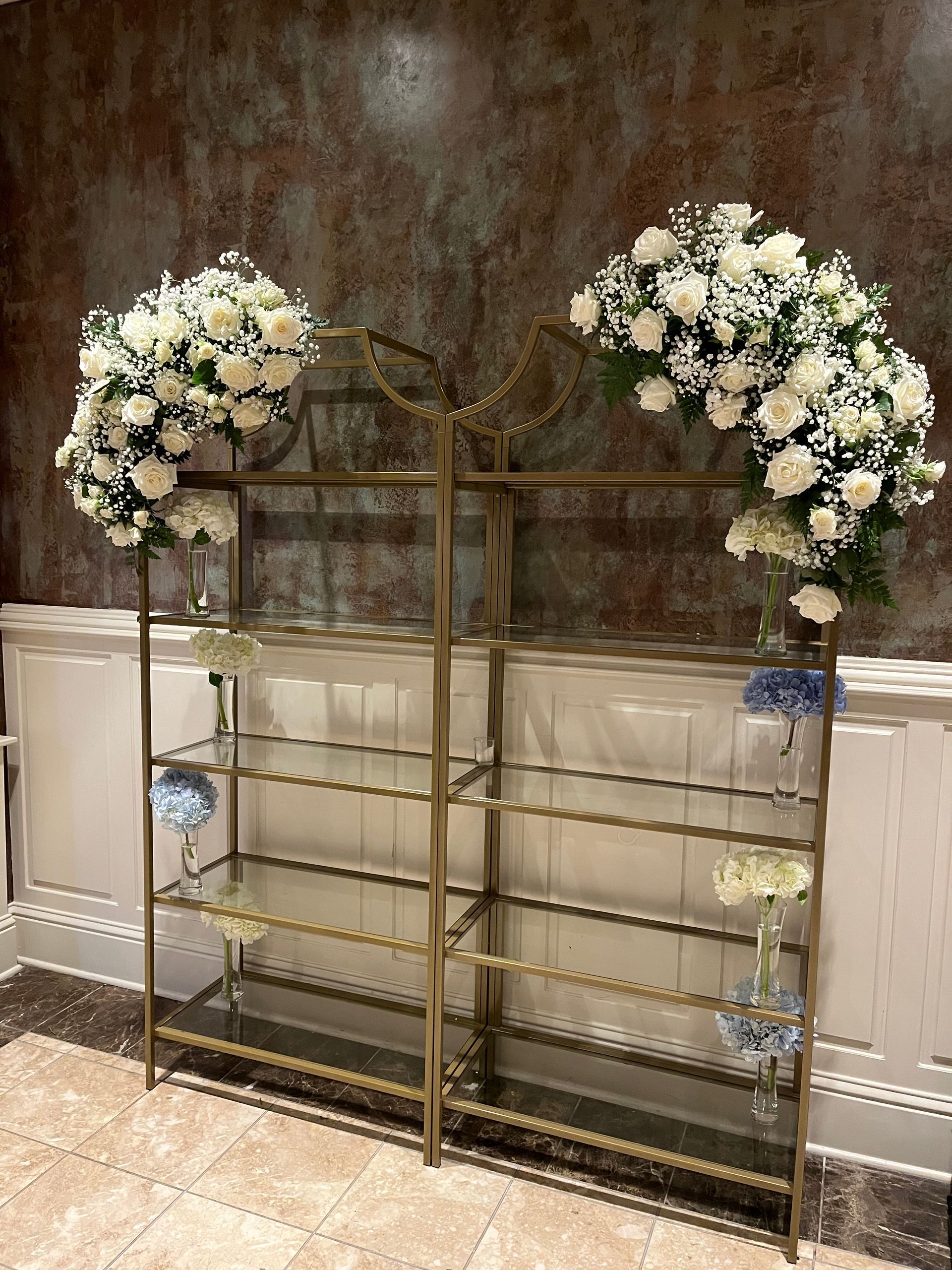 A glass shelf with flowers on top of it in a room.