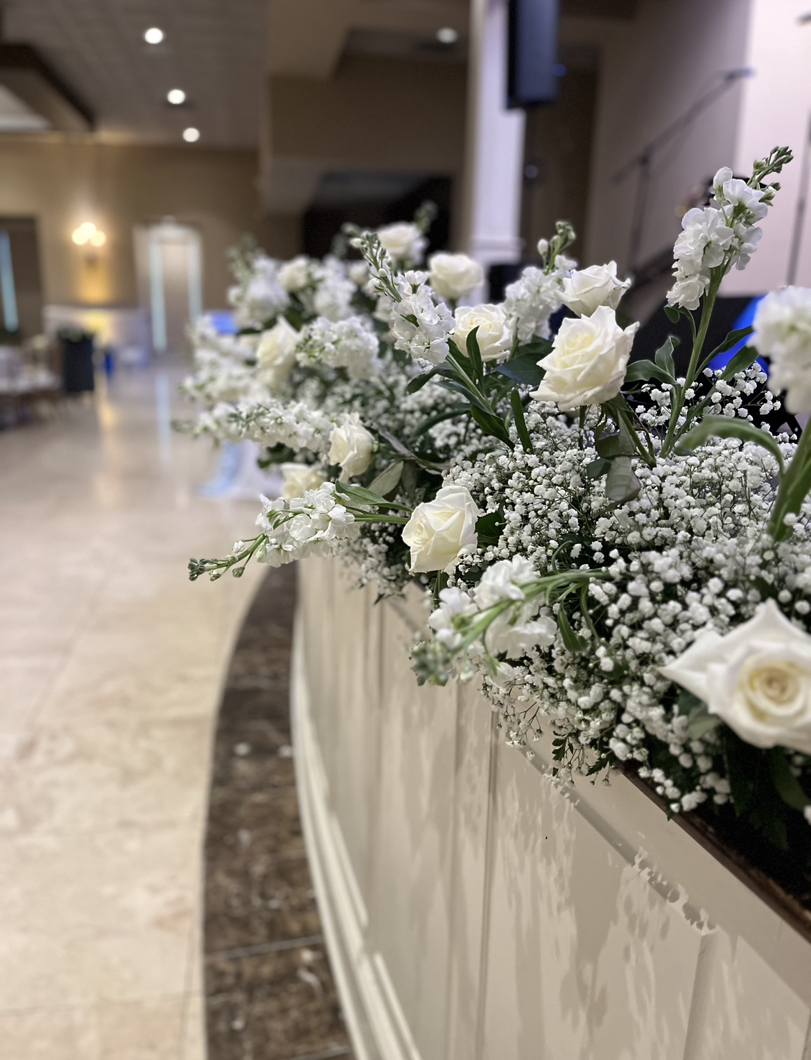A row of white flowers sitting on top of a wooden table.