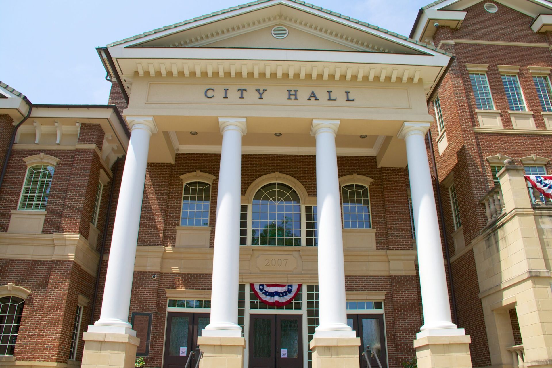 City Hall building with white columns and brick facade under a clear sky
