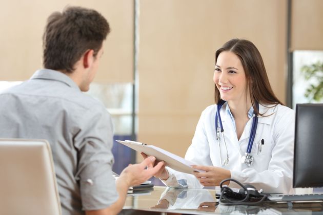 Doctor speaking with a patient across a desk in a bright clinic office