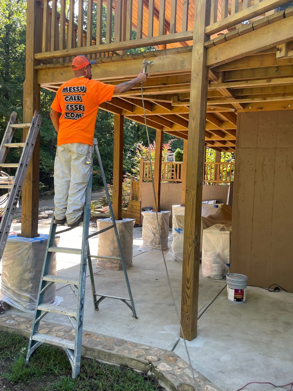 Worker in orange shirt using a ladder under a wooden deck during construction
