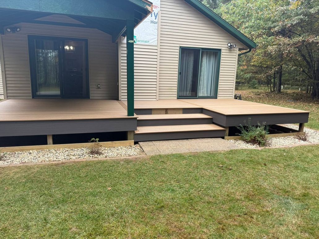 Front view of a small cabin with porch, steps, and sliding glass doors, set on a grassy yard.