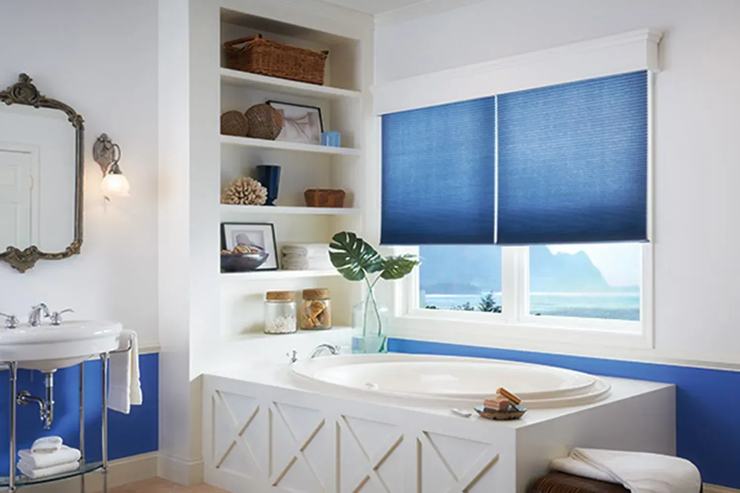 Blue bathroom with blinds, shelves, and a bathtub with ocean view.