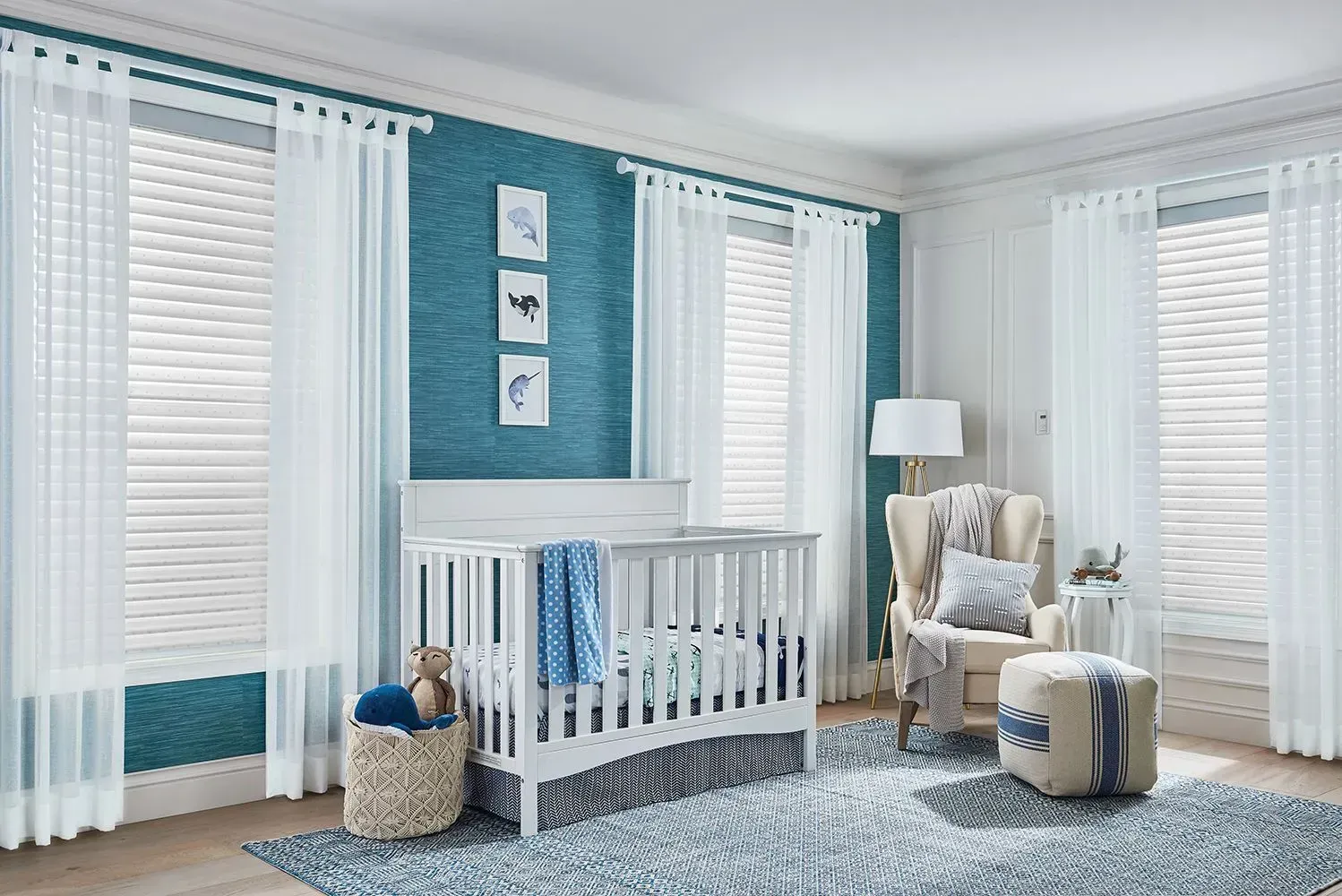 Nursery with white crib, blue wall, sheer curtains, and woven basket, in a bright, airy setting.