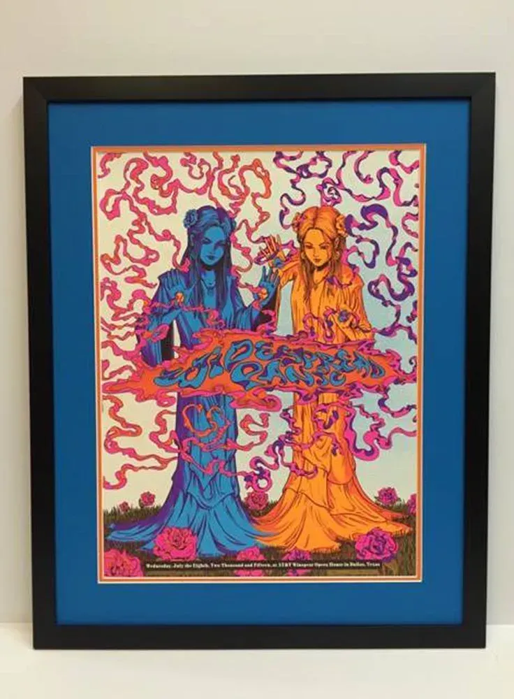 Framed artwork of two figures in blue and orange, surrounded by flower motifs, framed by blue and black.