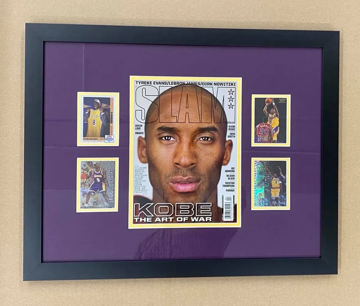 Framed Kobe Bryant magazine cover and four basketball cards, arranged on purple matting, black frame.