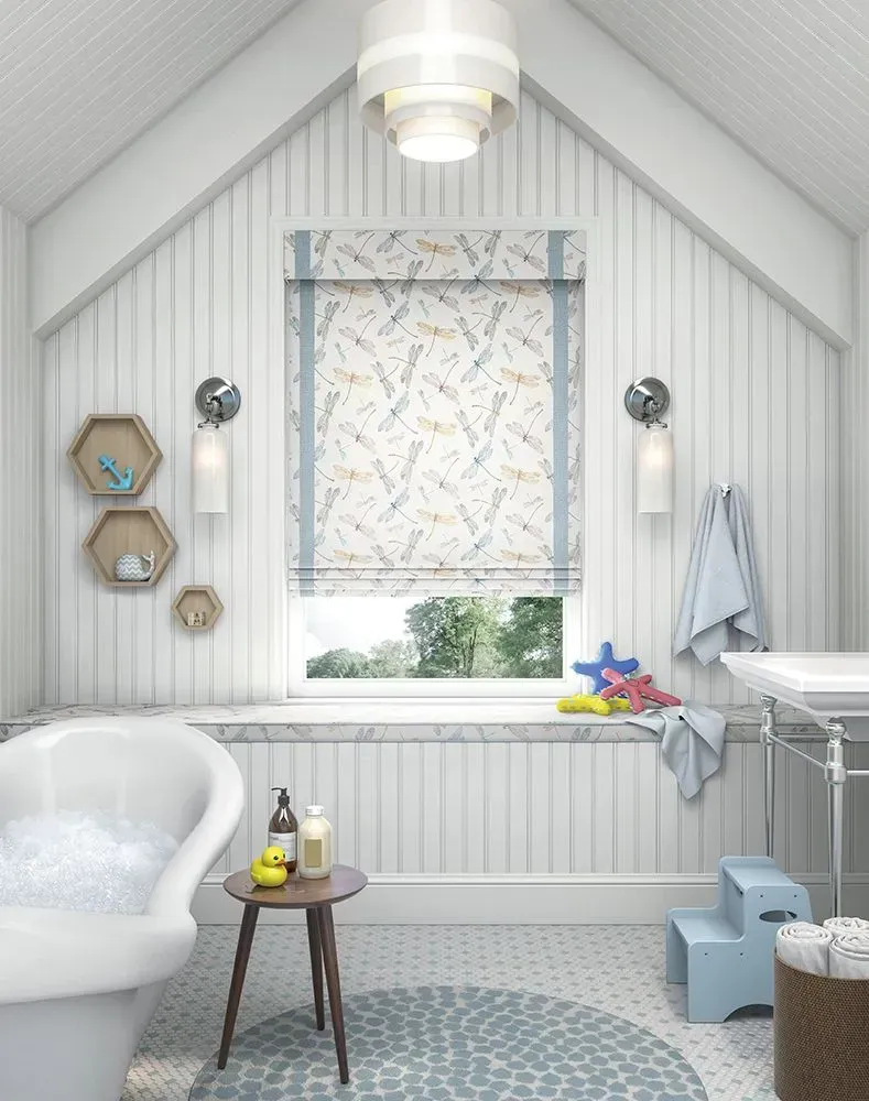 Bathroom with white paneling, bathtub, and patterned Roman shade.