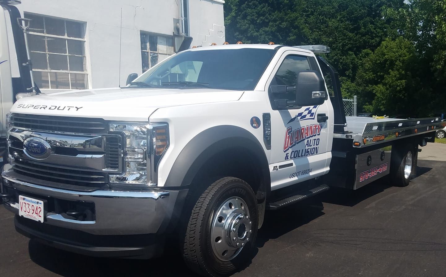 A white tow truck is parked in front of a building