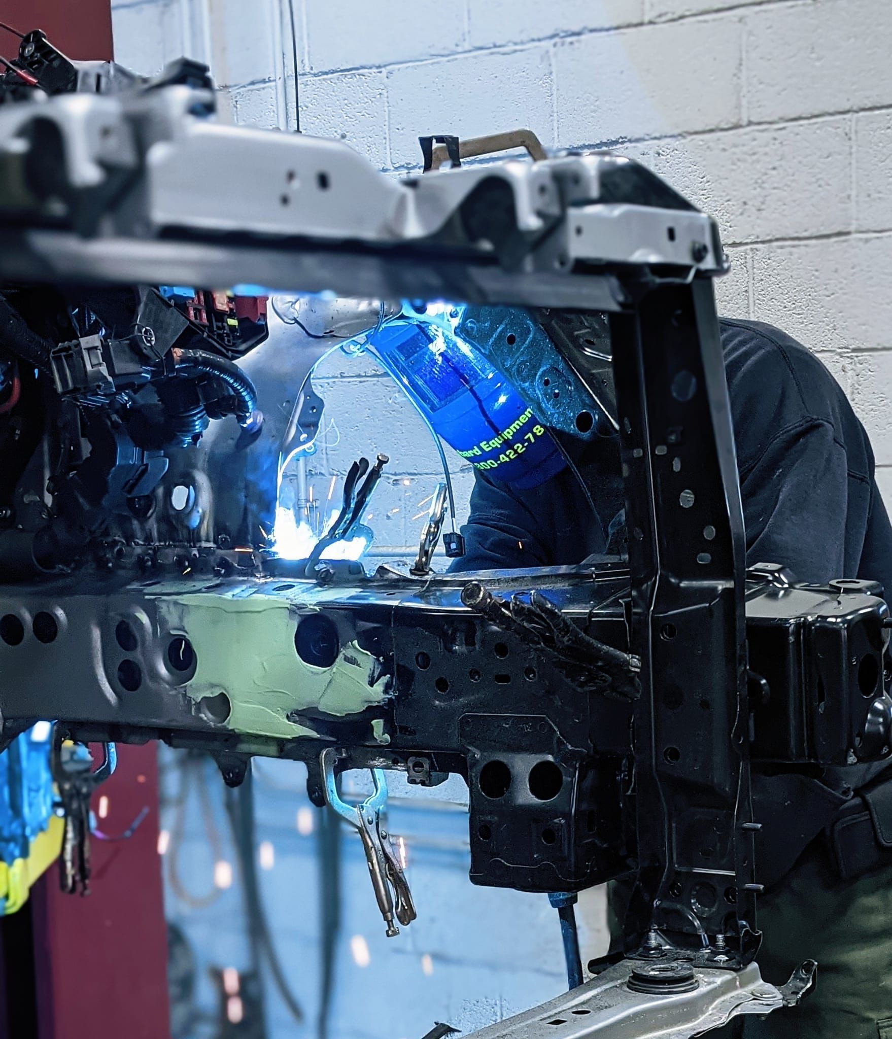 A man is welding a piece of metal in a garage.
