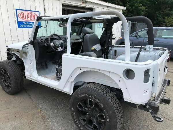 A white jeep is parked in front of a building.