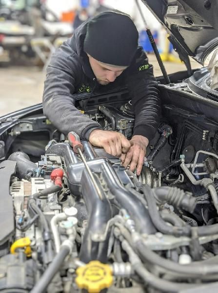A man is working on the engine of a car in a garage.