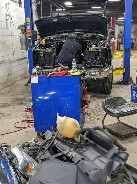 An automotive technician is working on a truck in a garage with the hood up.