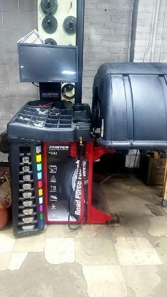 A tire balancing machine is sitting on the floor in a garage.