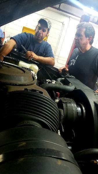 Two mechanics are working on a car engine in a garage